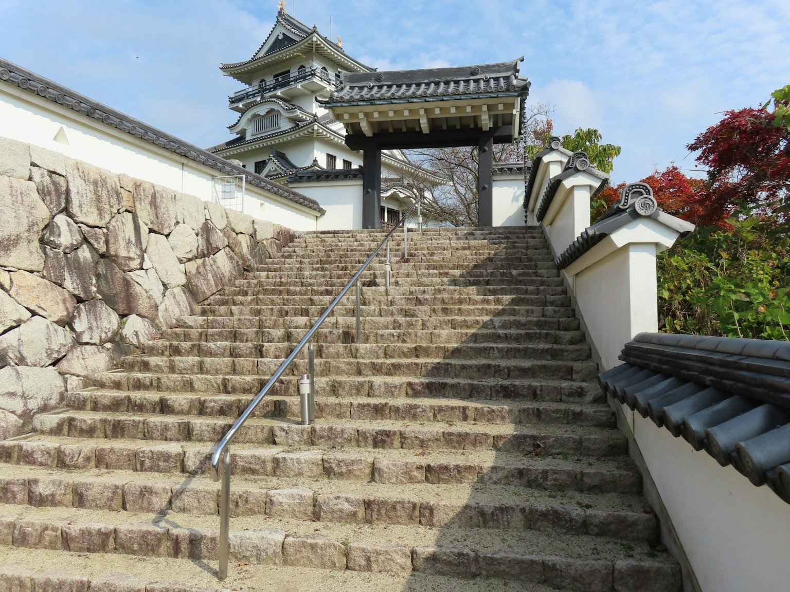 Escaleras de piedra que conducen a una puerta de castillo rodeada de árboles