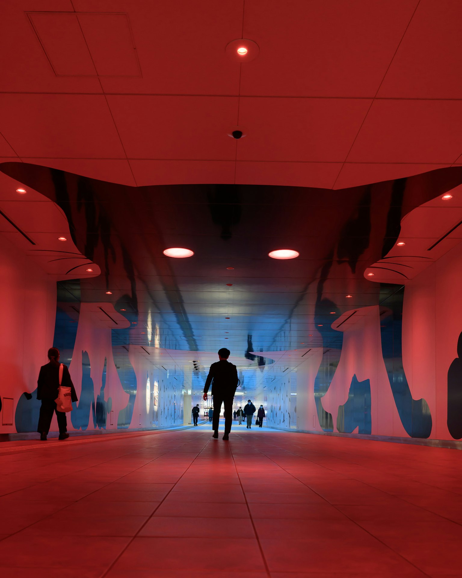 Silhouette seseorang berdiri di ruang futuristik dengan pencahayaan merah