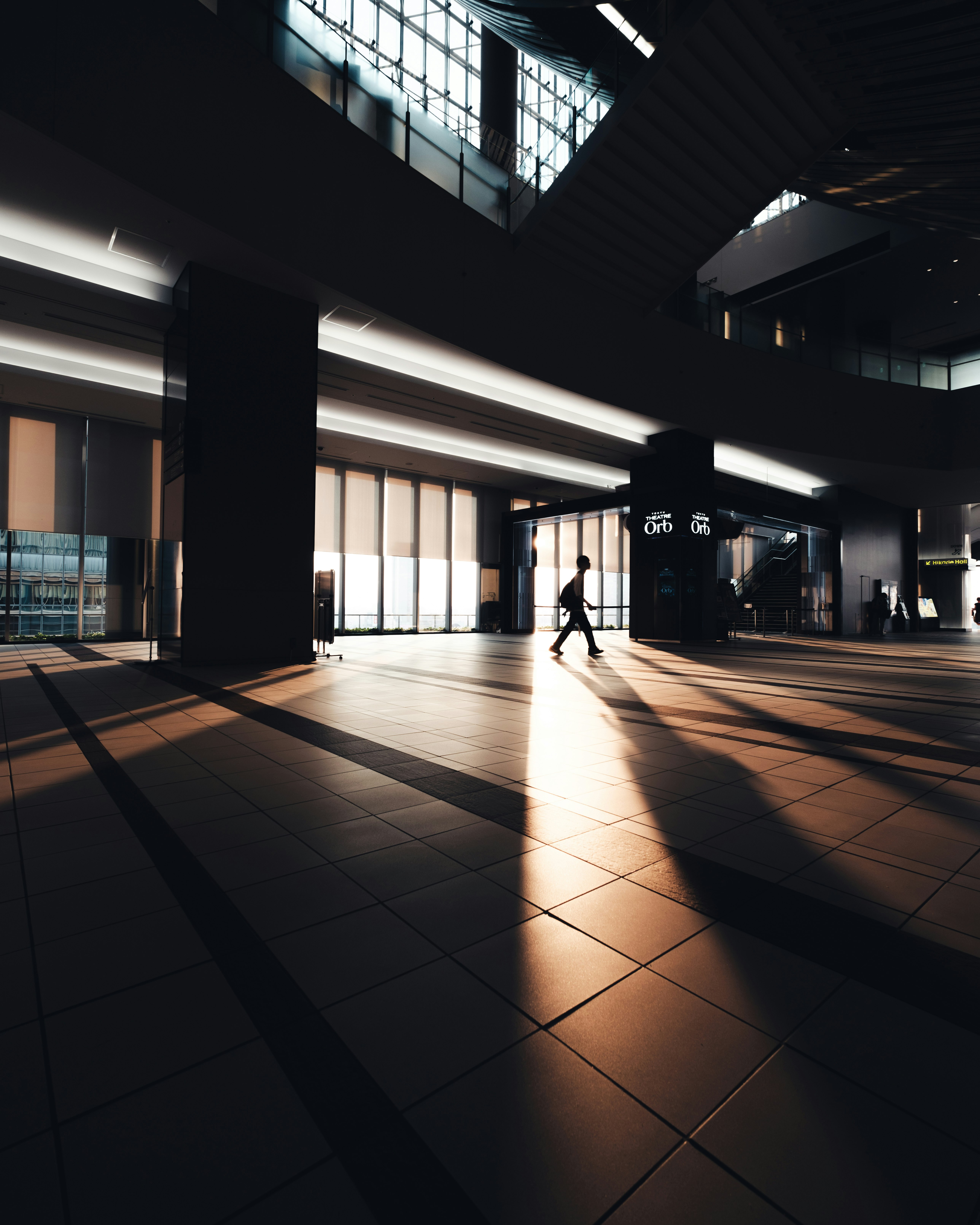 silhouette of a person walking through an indoor transit corridor