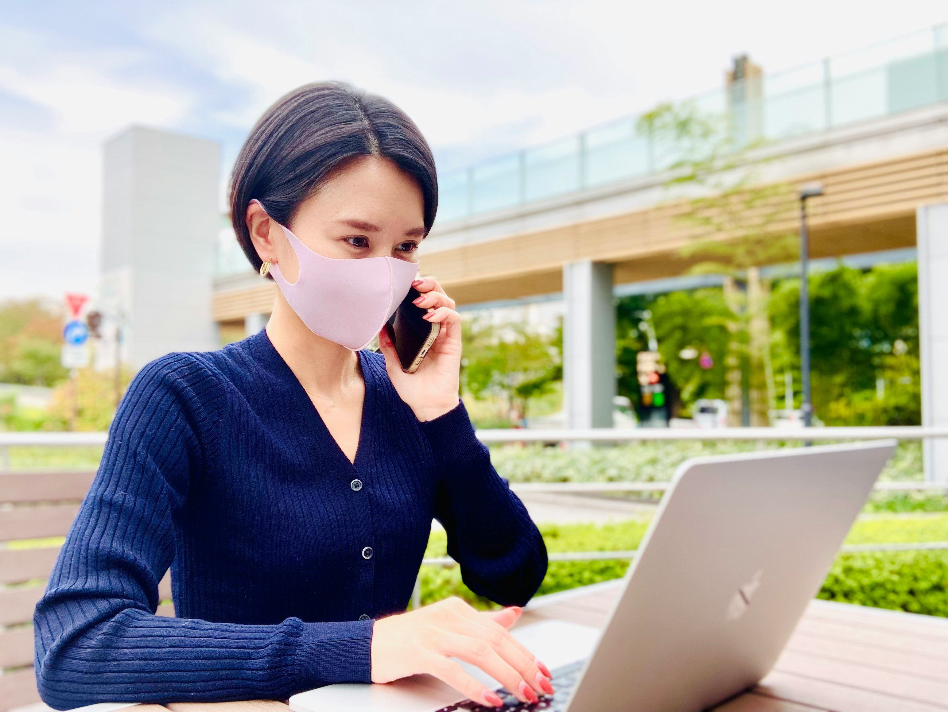 Donna con mascherina che usa un laptop all’aperto