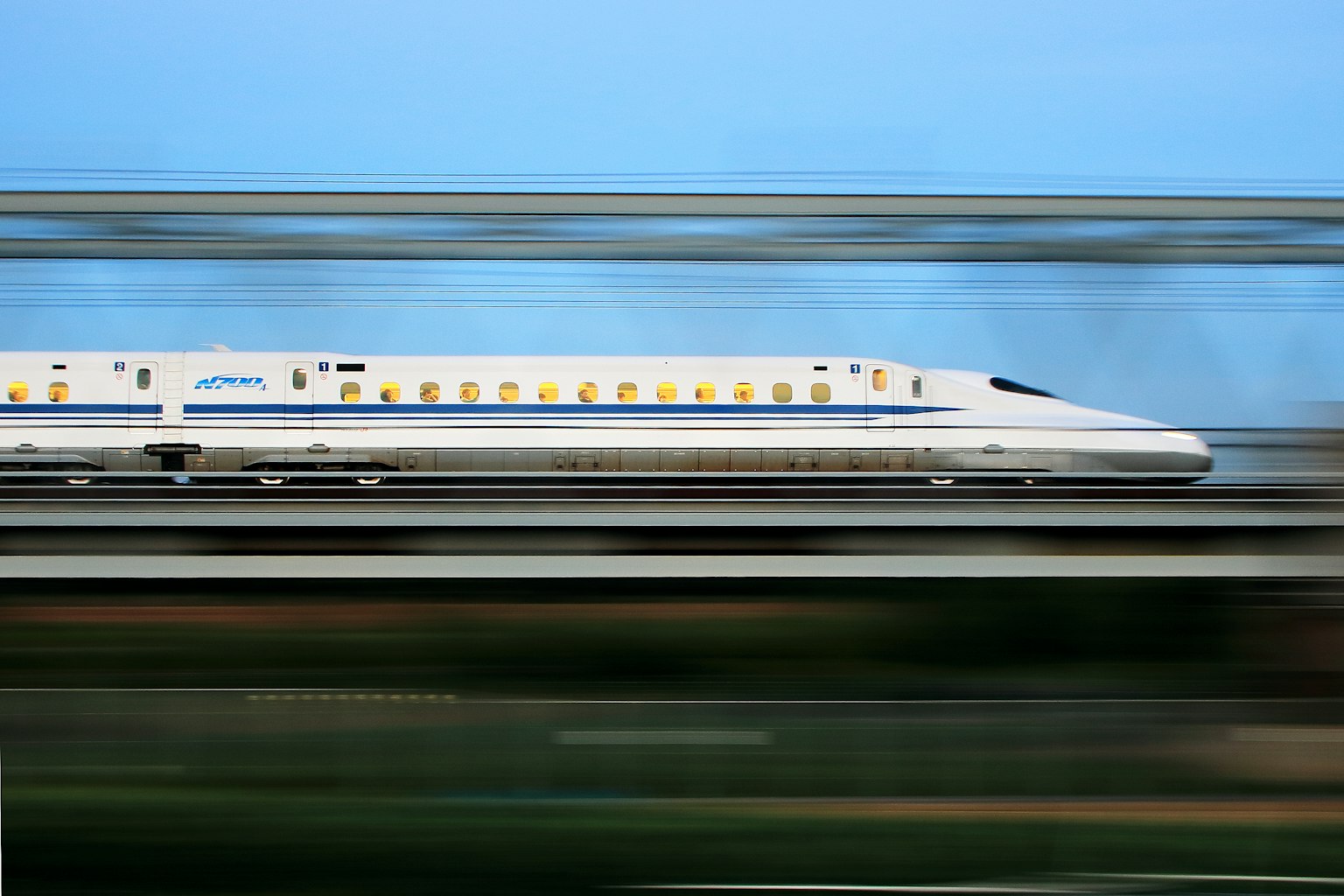 Shinkansen speeding through the countryside with a blurred background and clear blue sky