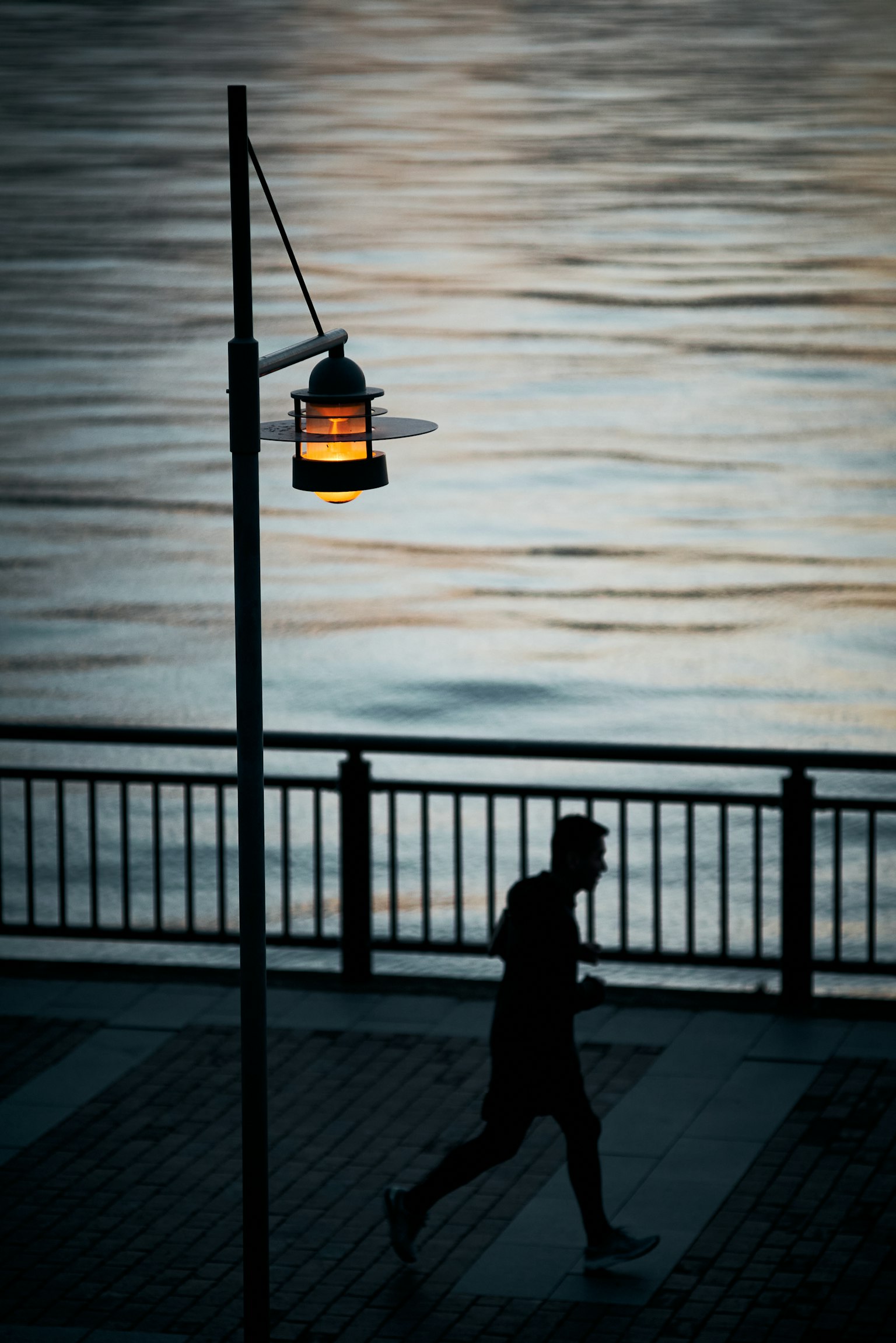 수변을 걷는 사람의 실루엣과 가로등