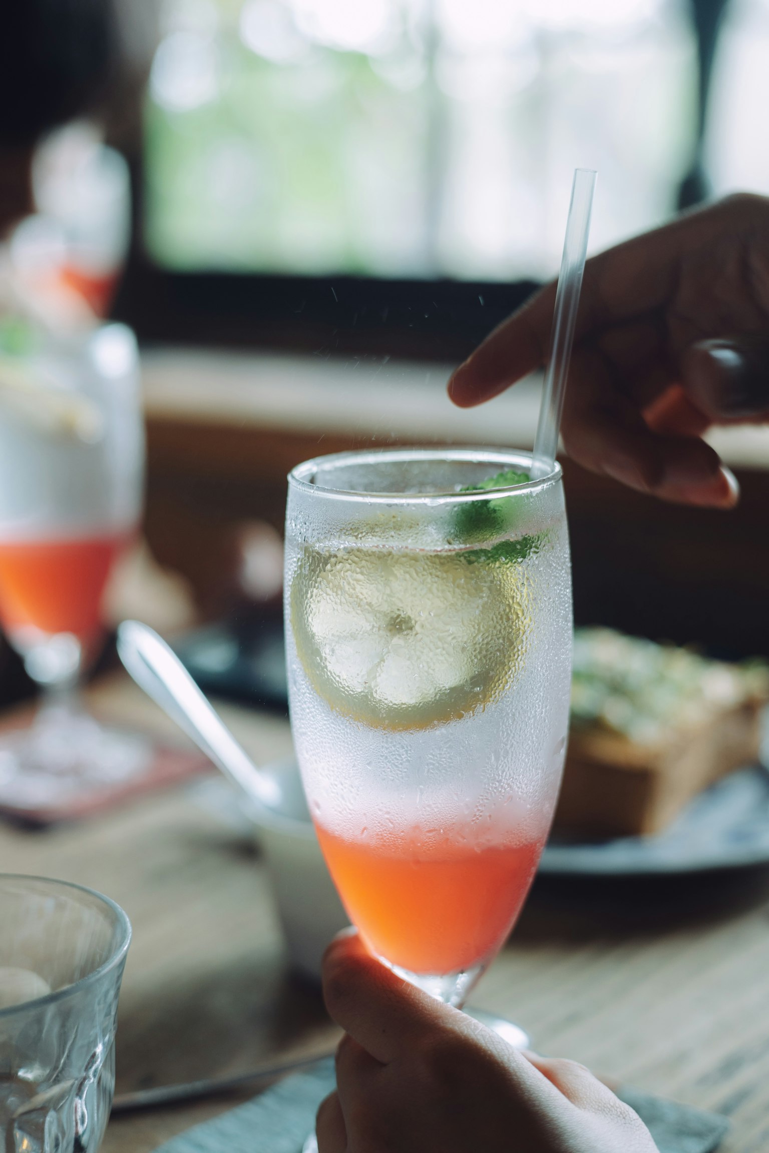 Une main tenant un verre de cocktail avec des tranches de citron et de lime