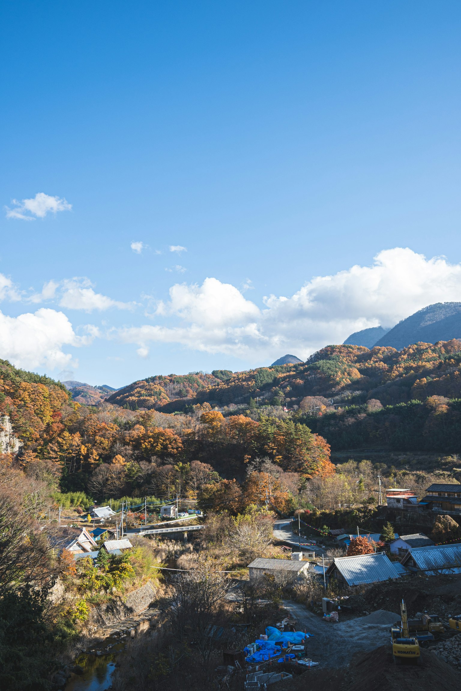 Malersiches Herbstland mit blauem Himmel Bergen bunten Bäumen und einem ruhigen Dorf