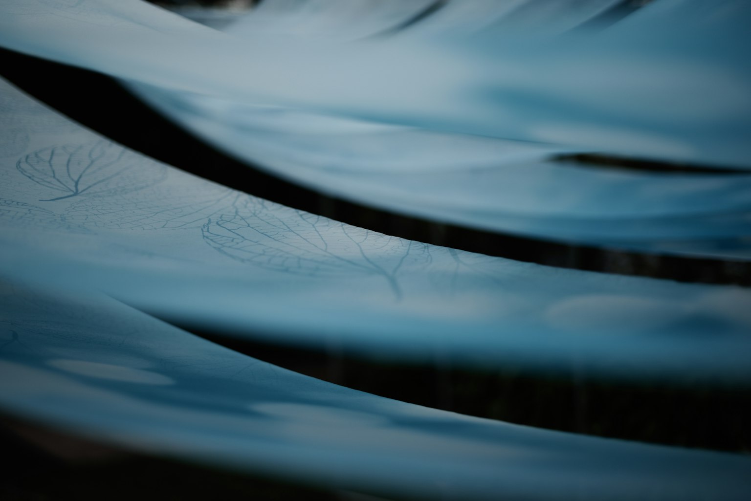 Gambar abstrak permukaan air biru dengan riak dan bayangan daun