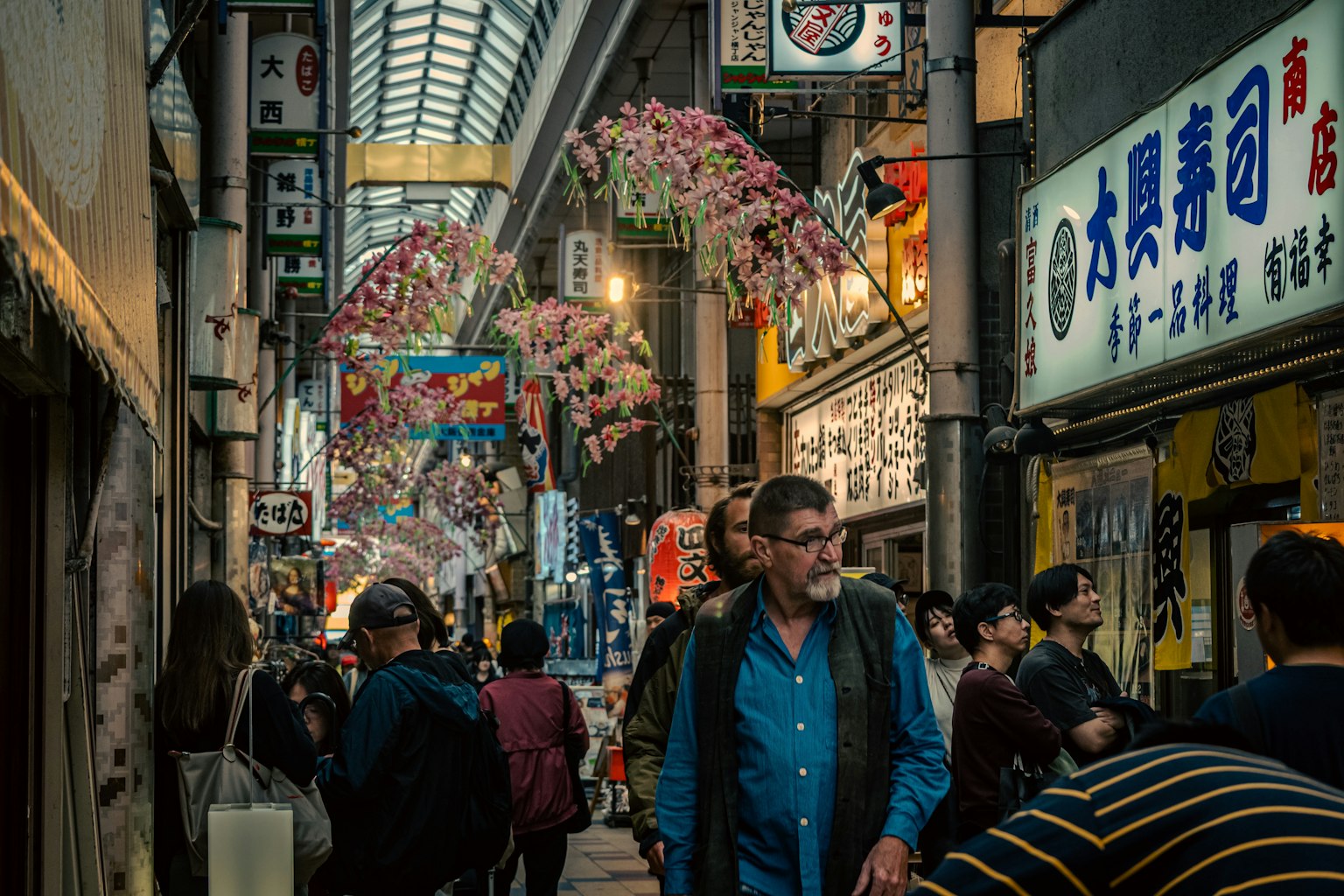 賑やかな商店街に人々が行き交う様子 色とりどりの花が飾られた屋根の下で
