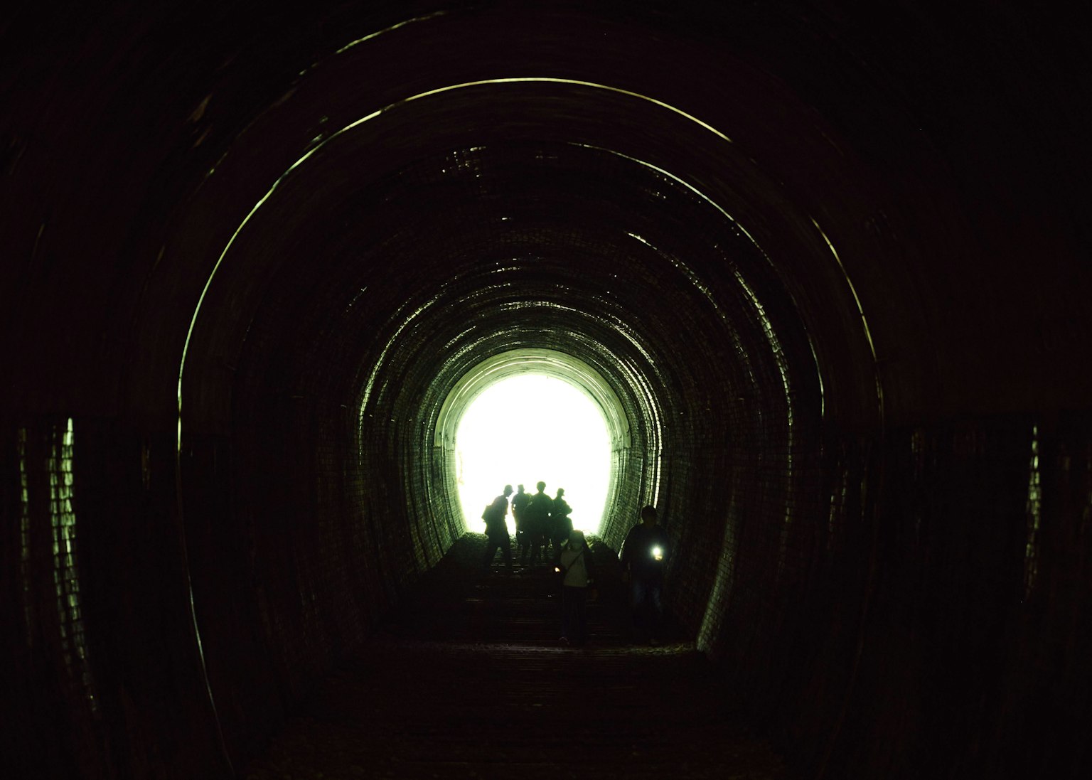 Luce brillante alla fine di un tunnel con silhouette di persone