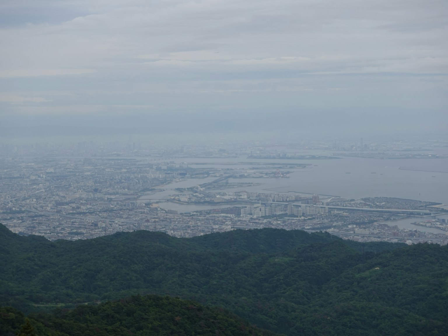 从山顶俯瞰城市和海洋的全景 多云的天空和绿色的山丘