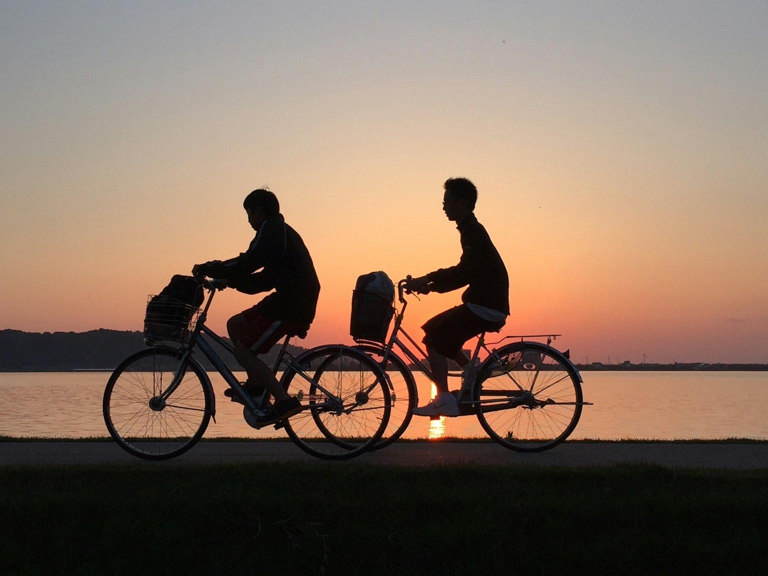 Silhouette de deux personnes faisant du vélo au coucher du soleil