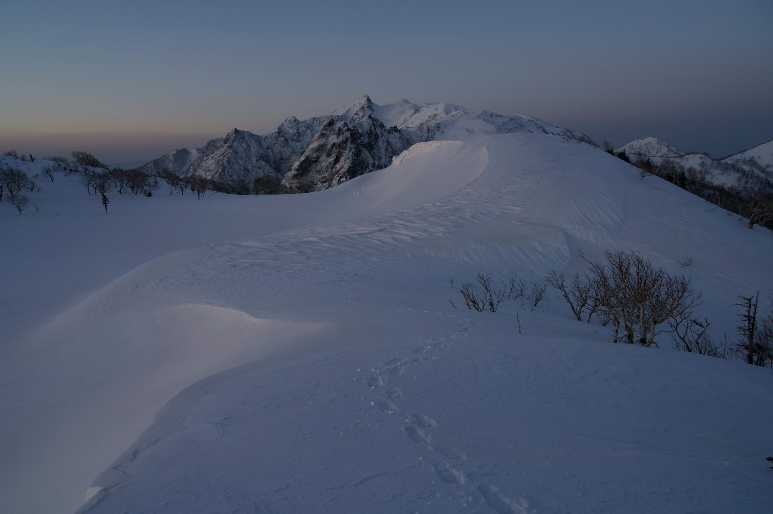 Paisaje montañoso cubierto de nieve con cielo crepuscular