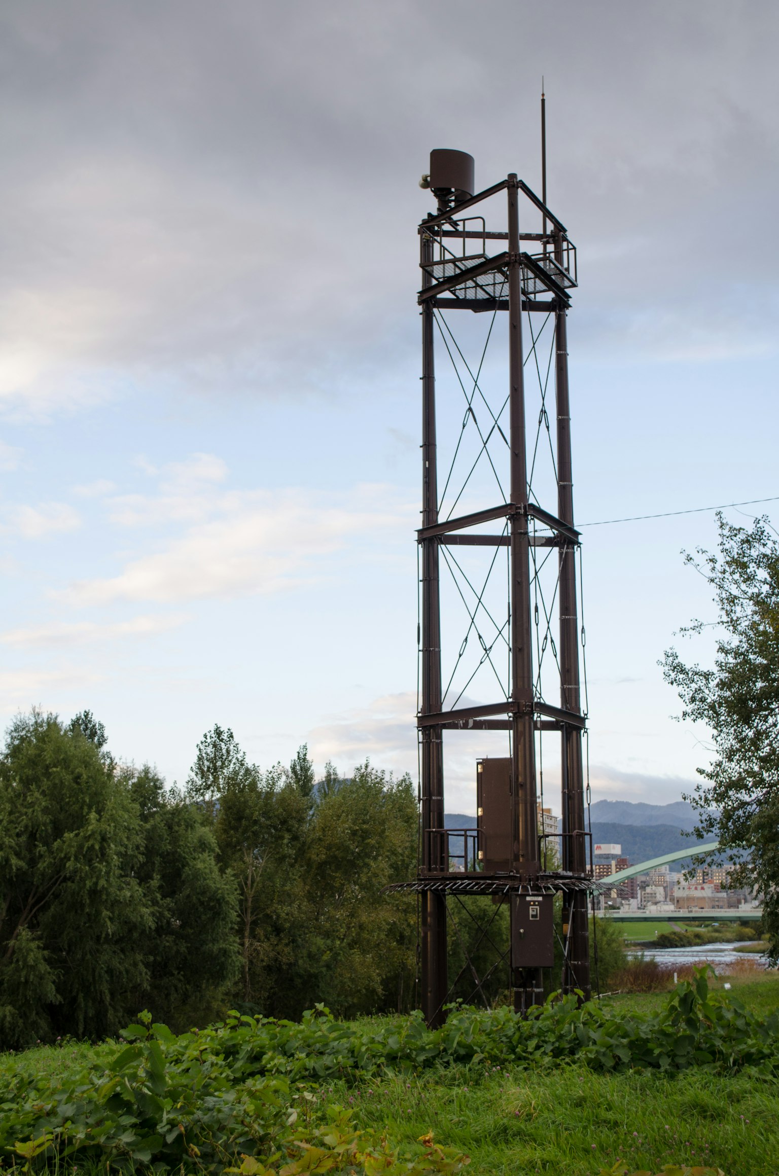 Torre metallica arrugginita con prato verde e cielo nuvoloso