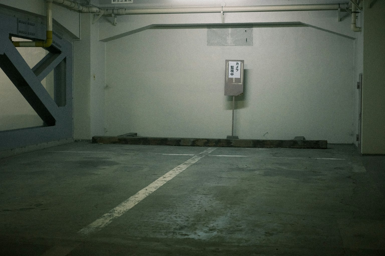 Esquina de estacionamiento vacía con paredes verdes y suelo de concreto que presenta un espacio de estacionamiento y un viejo parquímetro