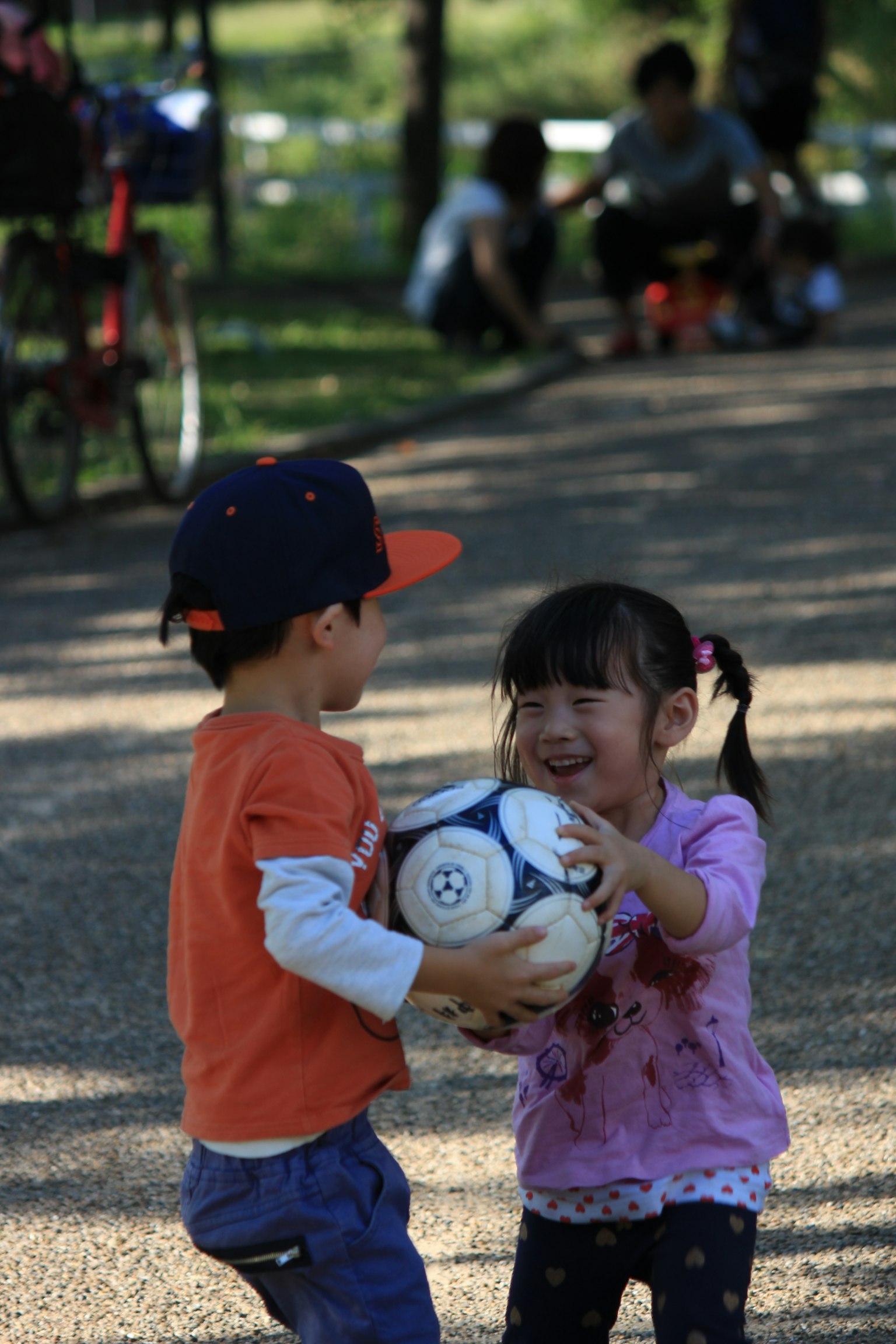 Dos niños jugando con un balón de fútbol en un parque