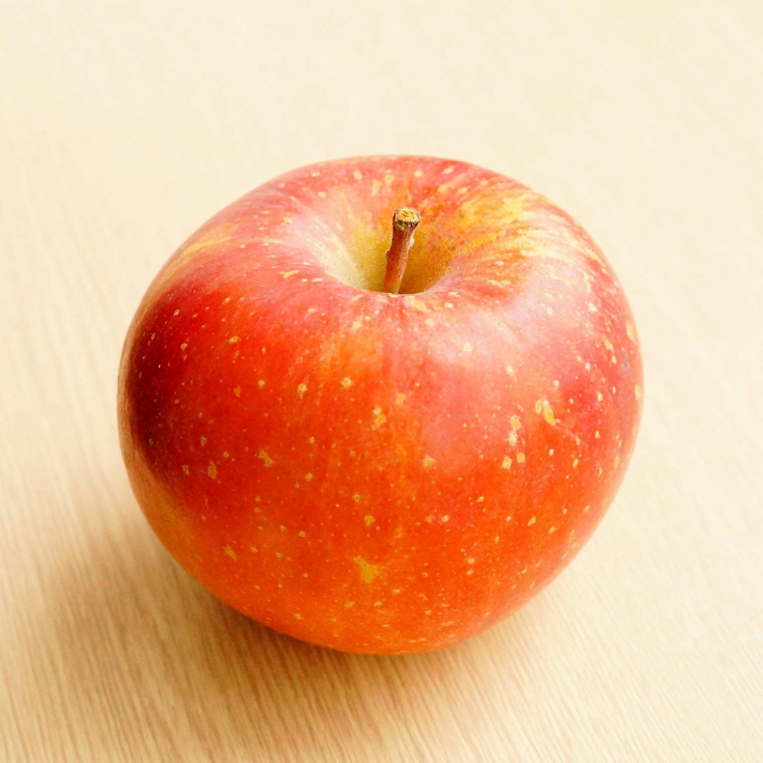 Une pomme rouge est posée sur une table en bois