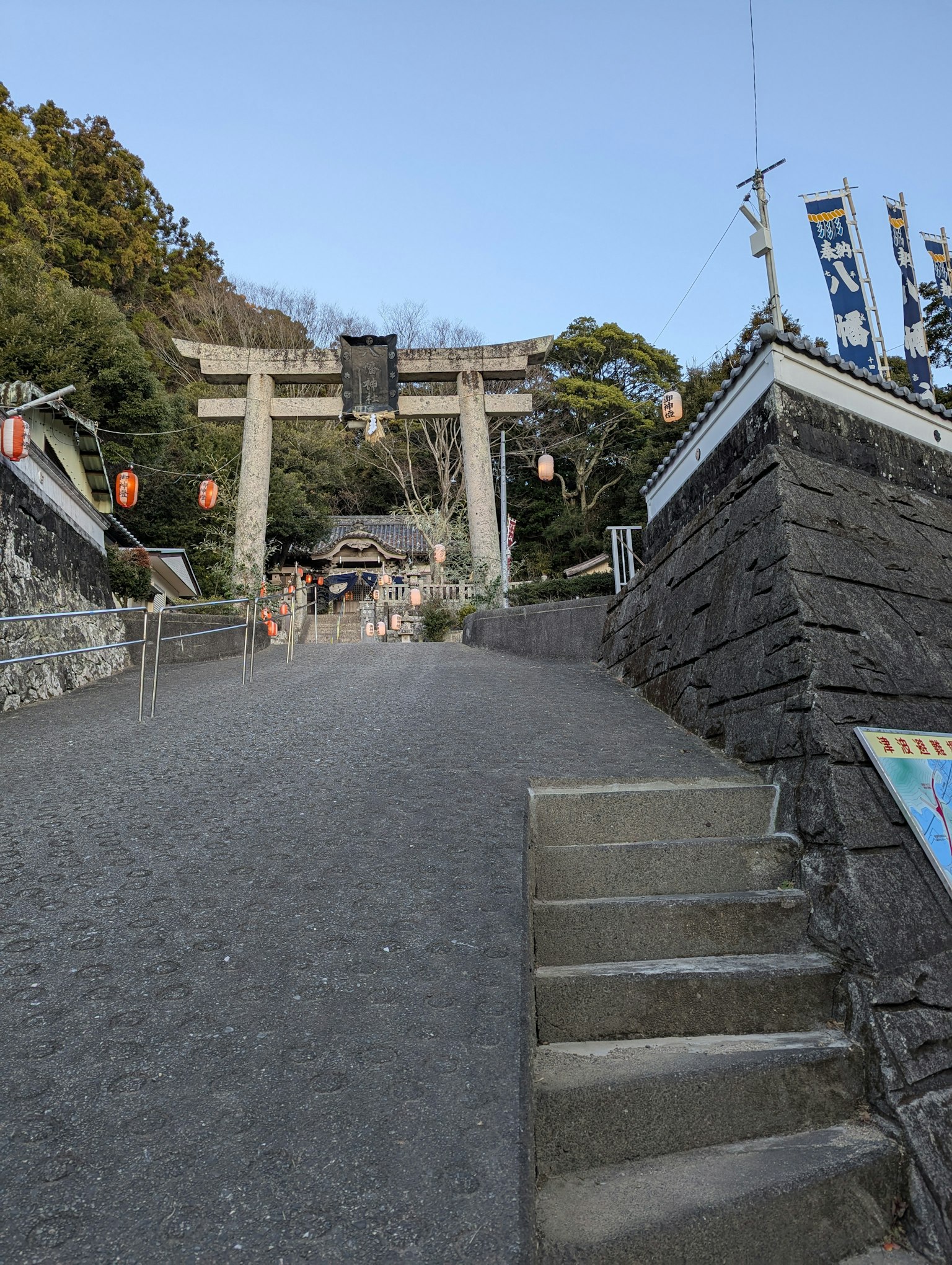 Blick auf einen Schrein mit einem Torii und steinernen Stufen, die nach oben führen