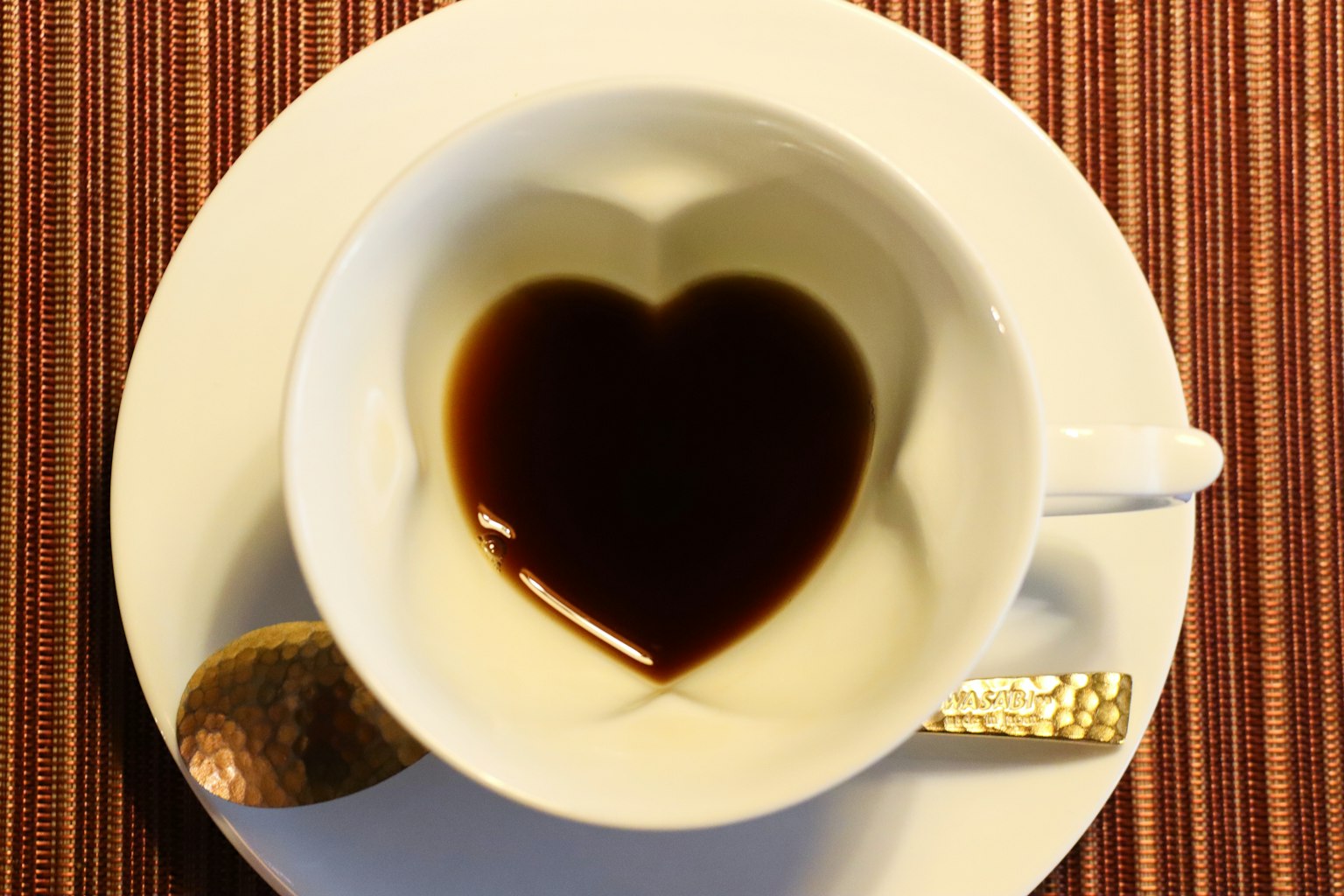 Kaffeetasse mit herzförmigem Muster in der Flüssigkeit auf einer weißen Untertasse