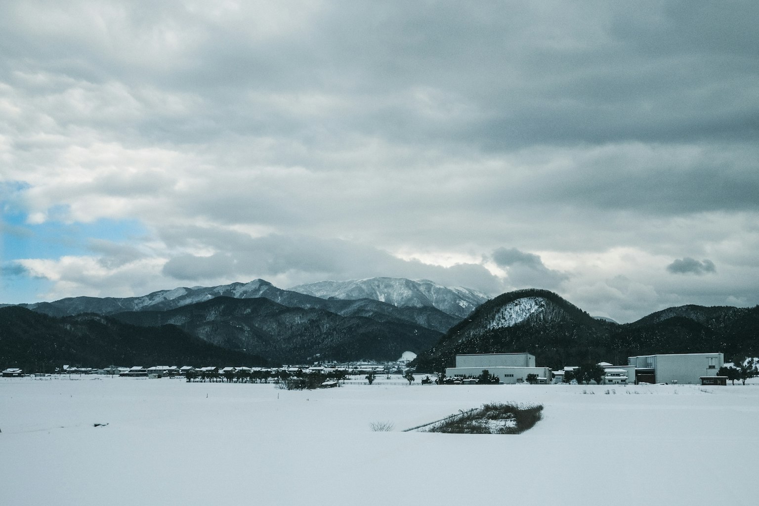雪覆盖的平原和背景中的山脉以及多云的天空