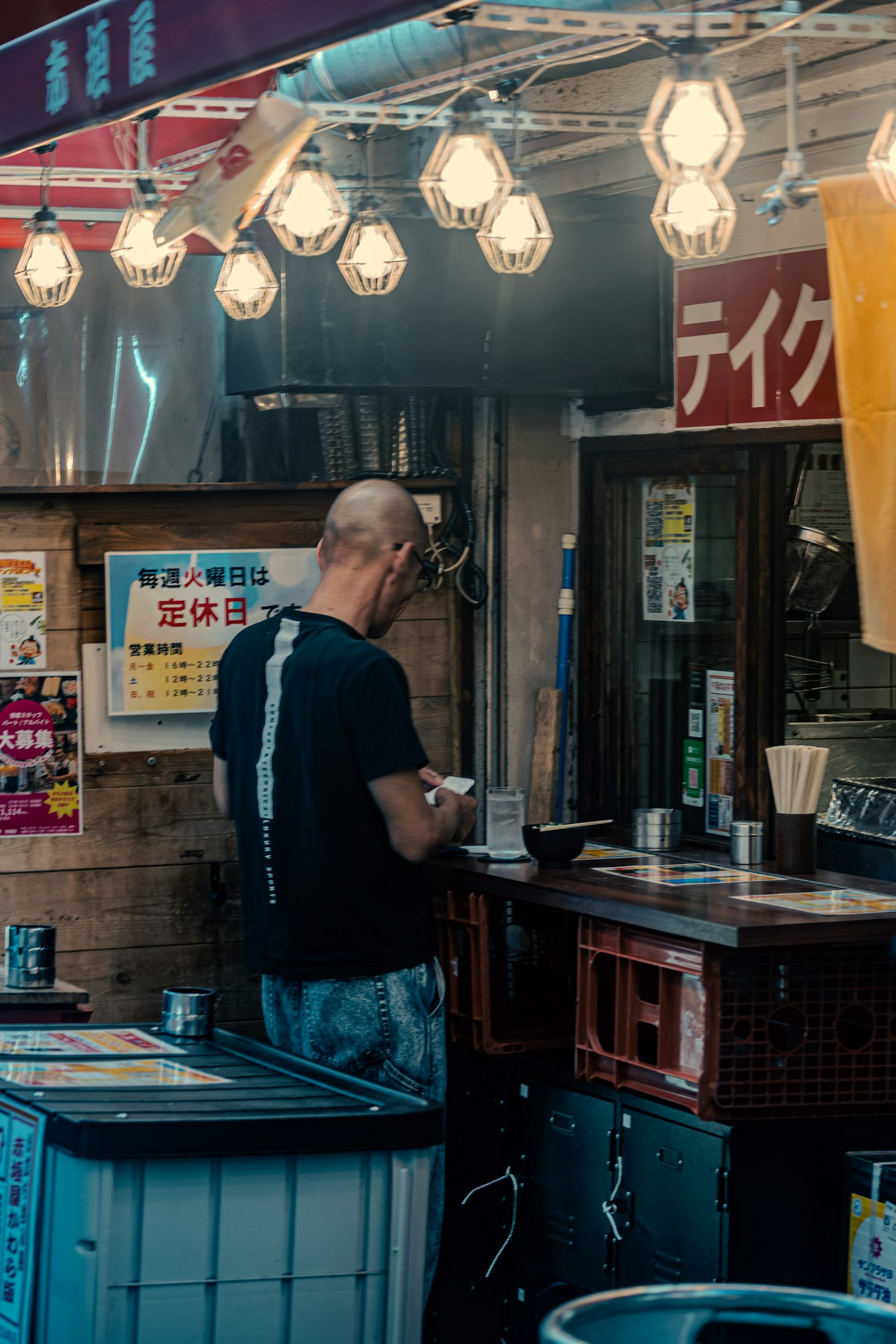 Homme utilisant un smartphone devant un stand de nourriture ampoules lumineuses suspendues au-dessus