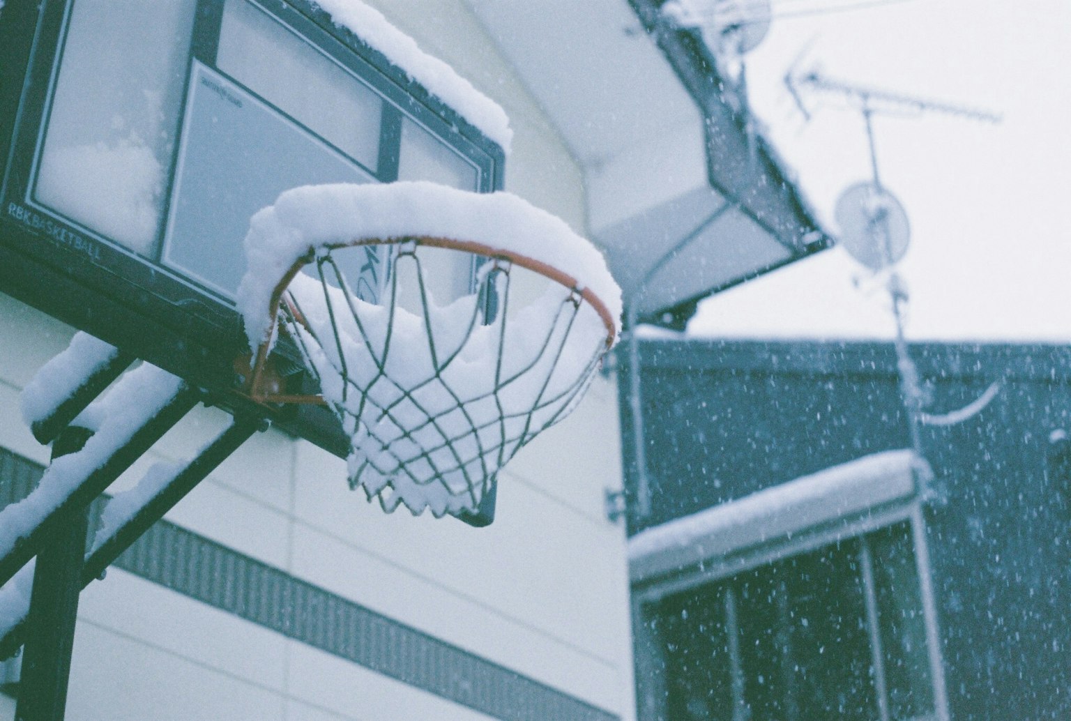 Keranjang basket tertutup salju dengan rumah di latar belakang