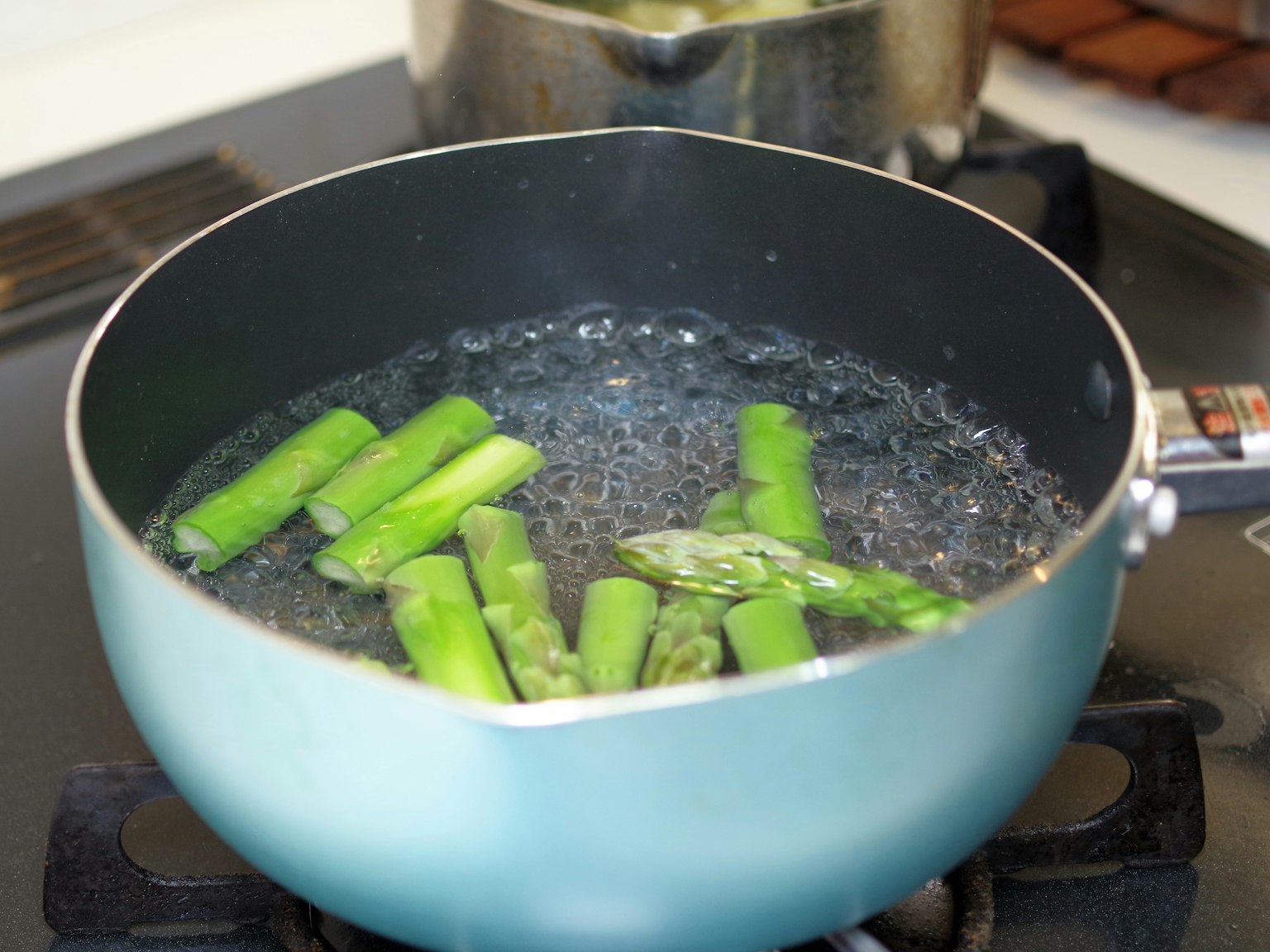 Green asparagus spears boiling in a pot of water