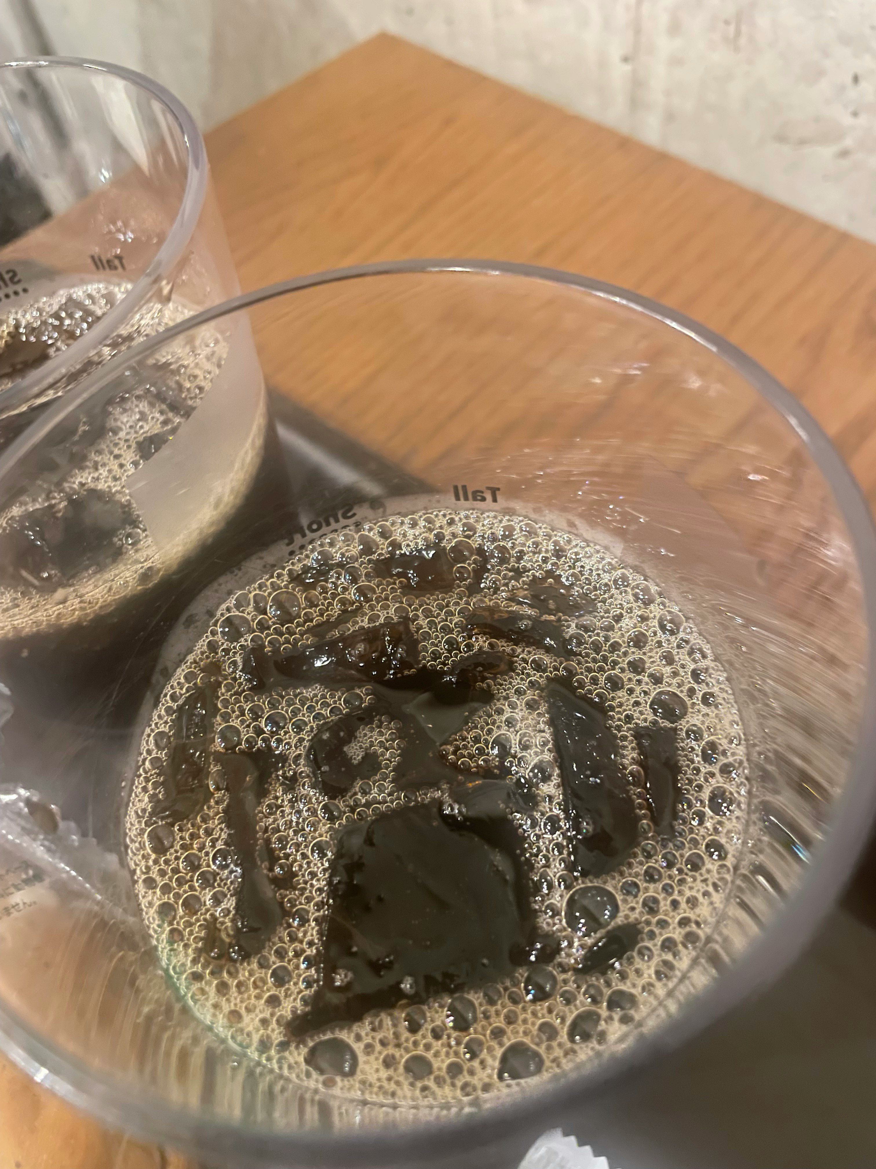 氷入りのアイスコーヒーのグラスと泡立つ液面