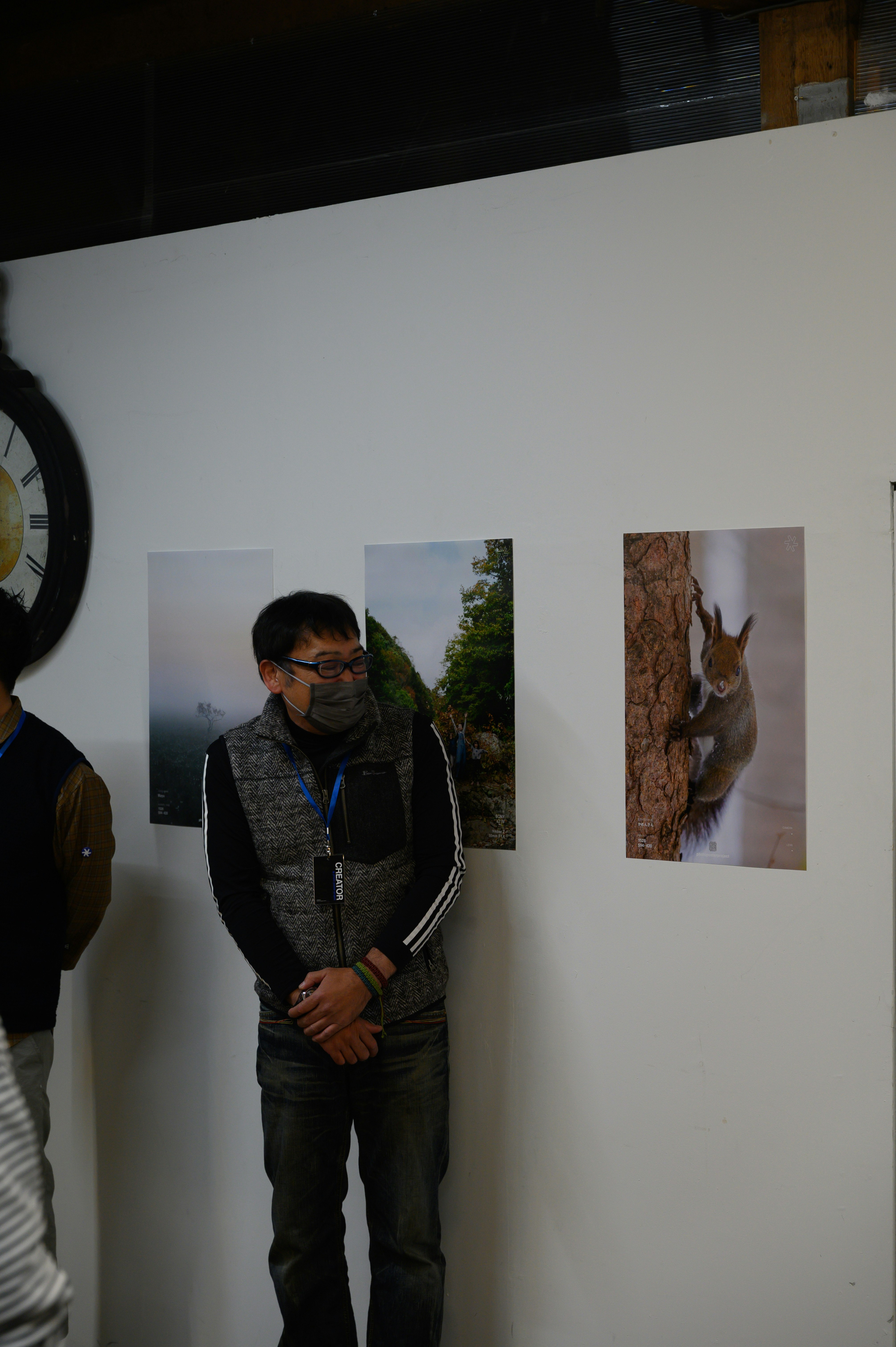 personne portant un masque dans une salle d’exposition avec des tirages photo d’animaux