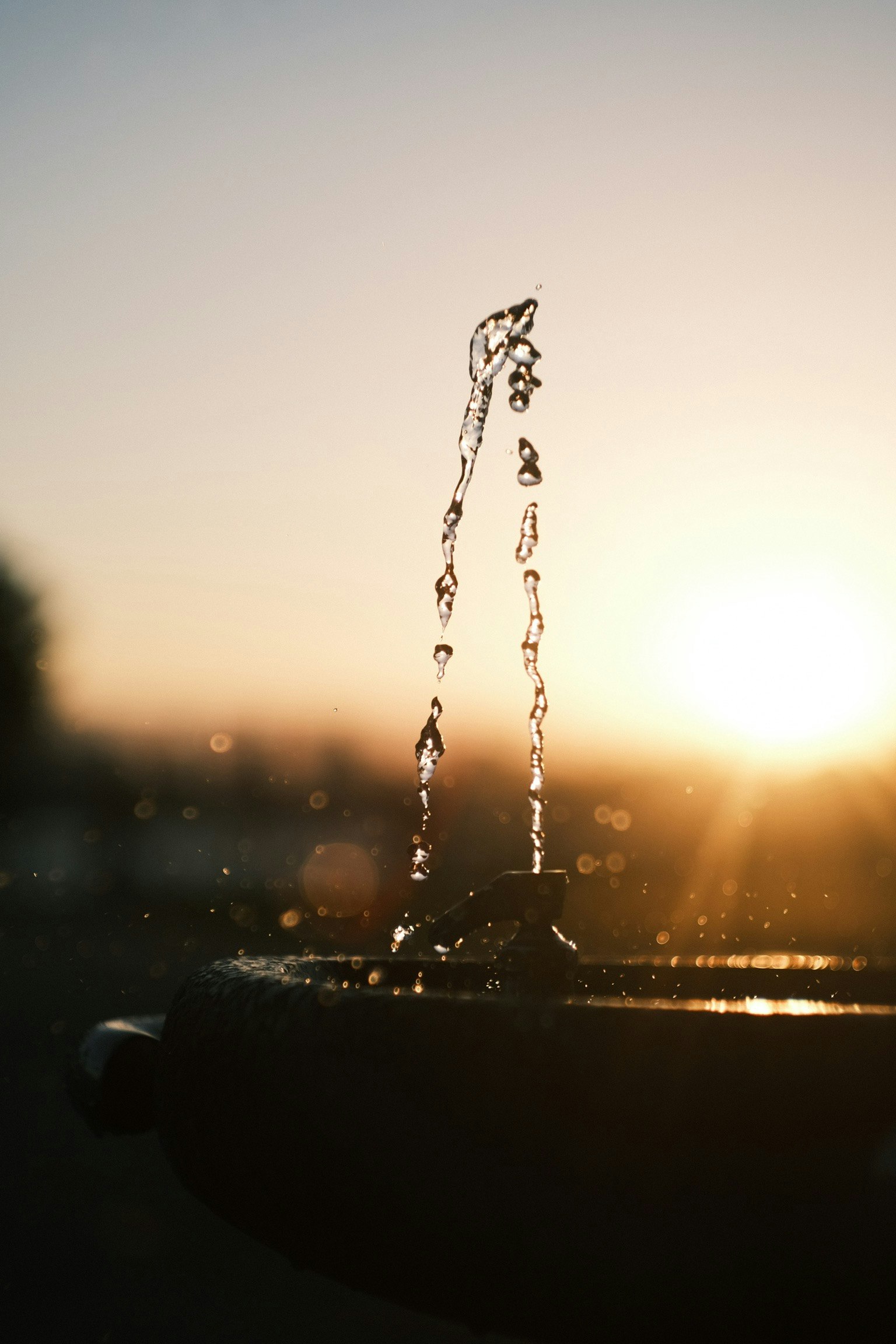 水の噴水が夕日を背景にしている美しいシーン