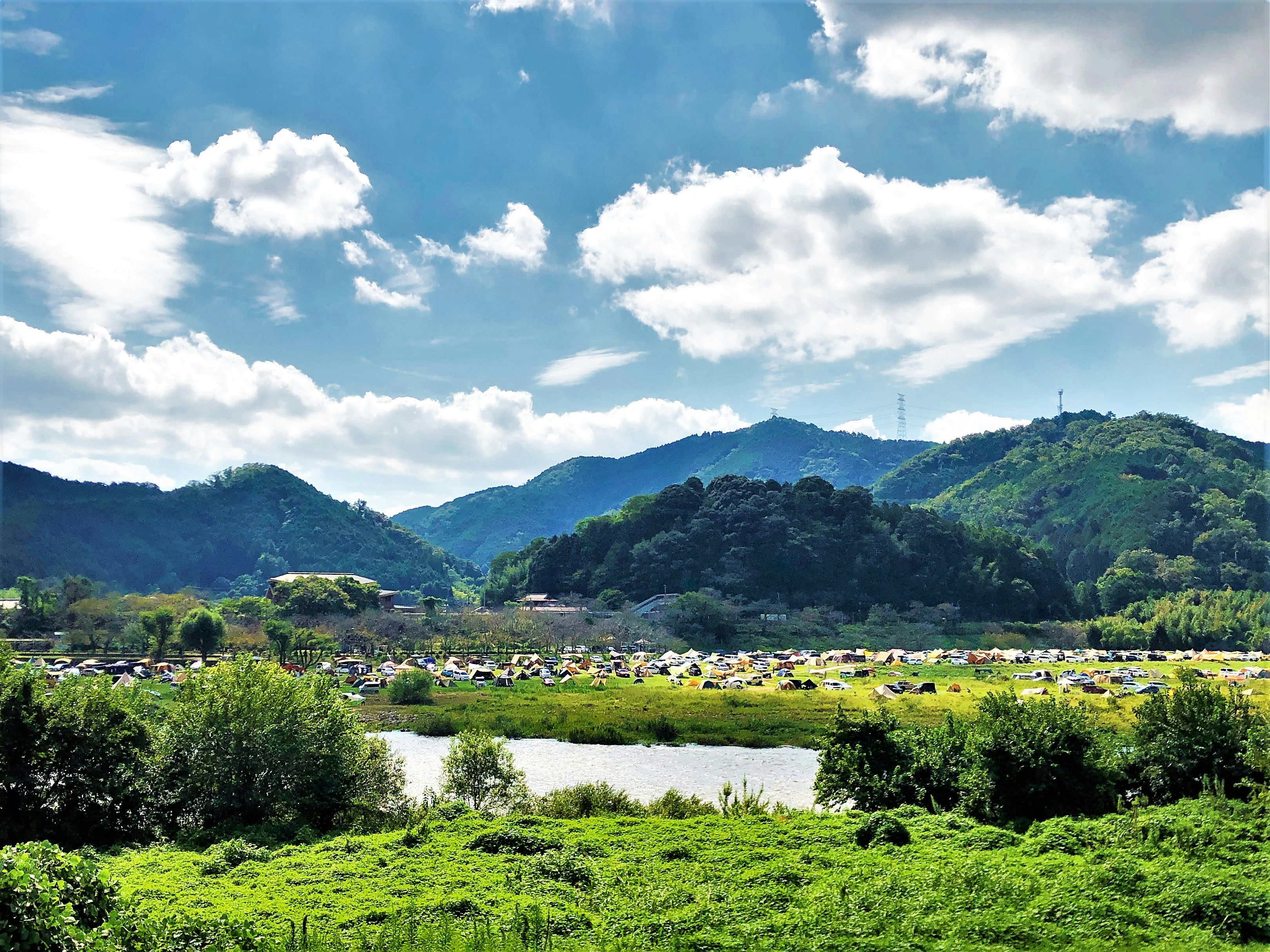 川と緑の草地、山並みが広がる自然風景