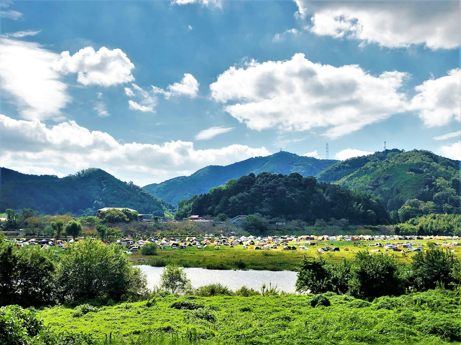 Landscape with blue sky and white clouds green mountains and a river
