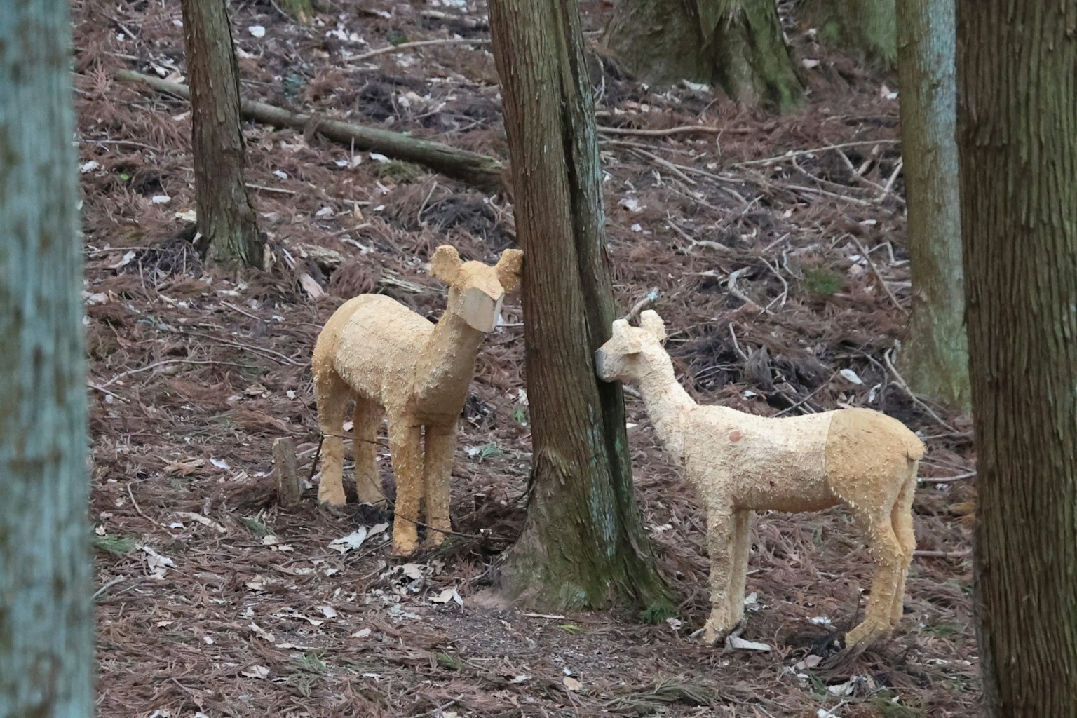 Deux sculptures d'animaux se tenant près d'un arbre dans la forêt