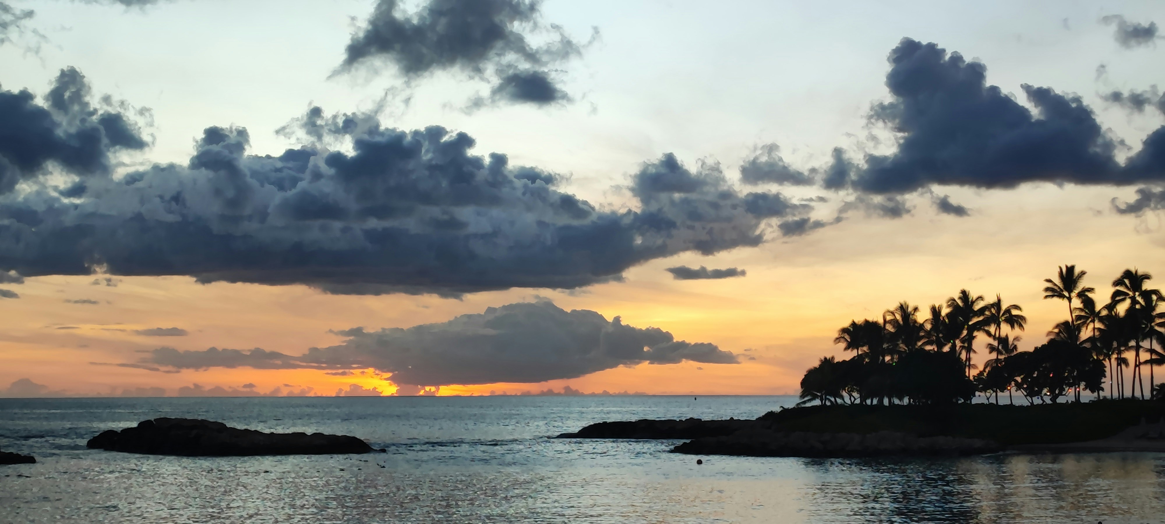 夕焼けの海とヤシの並ぶ小島の風景
