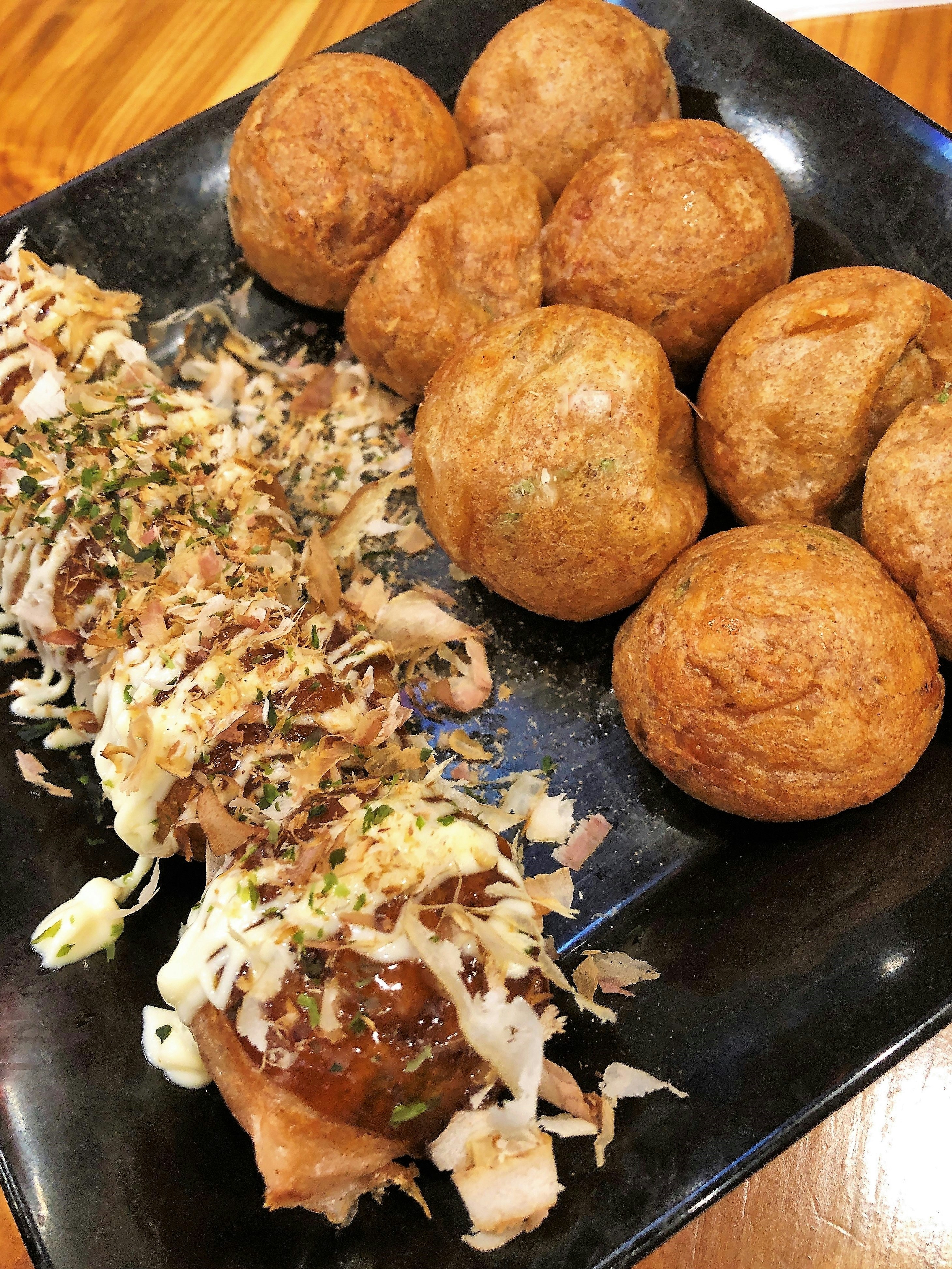 bánh chiên tròn kiểu takoyaki trên đĩa đen với bắp cải băm nhỏ