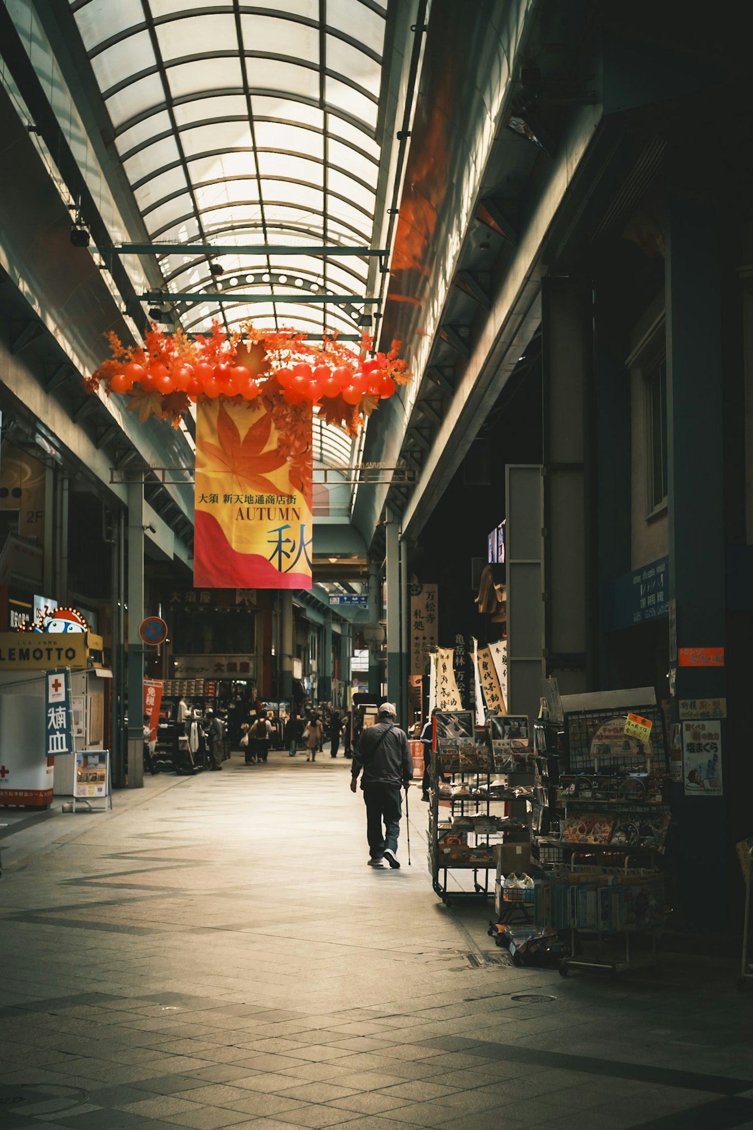 Bagian dalam arcade komersial dengan seseorang yang berjalan dan dekorasi merah tergantung dari langit-langit