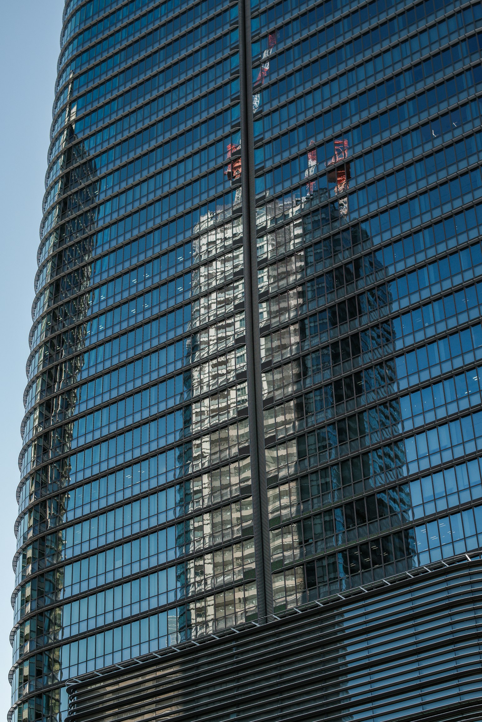 Refleksi gedung pencakar langit di jendela kaca dengan langit biru