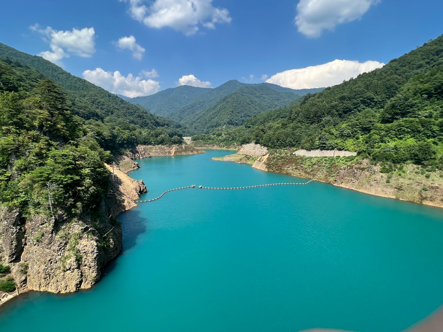 ทิวทัศน์ที่สวยงามของทะเลสาบสีเทอร์ควอยซ์ที่ล้อมรอบด้วยภูเขาสีเขียว