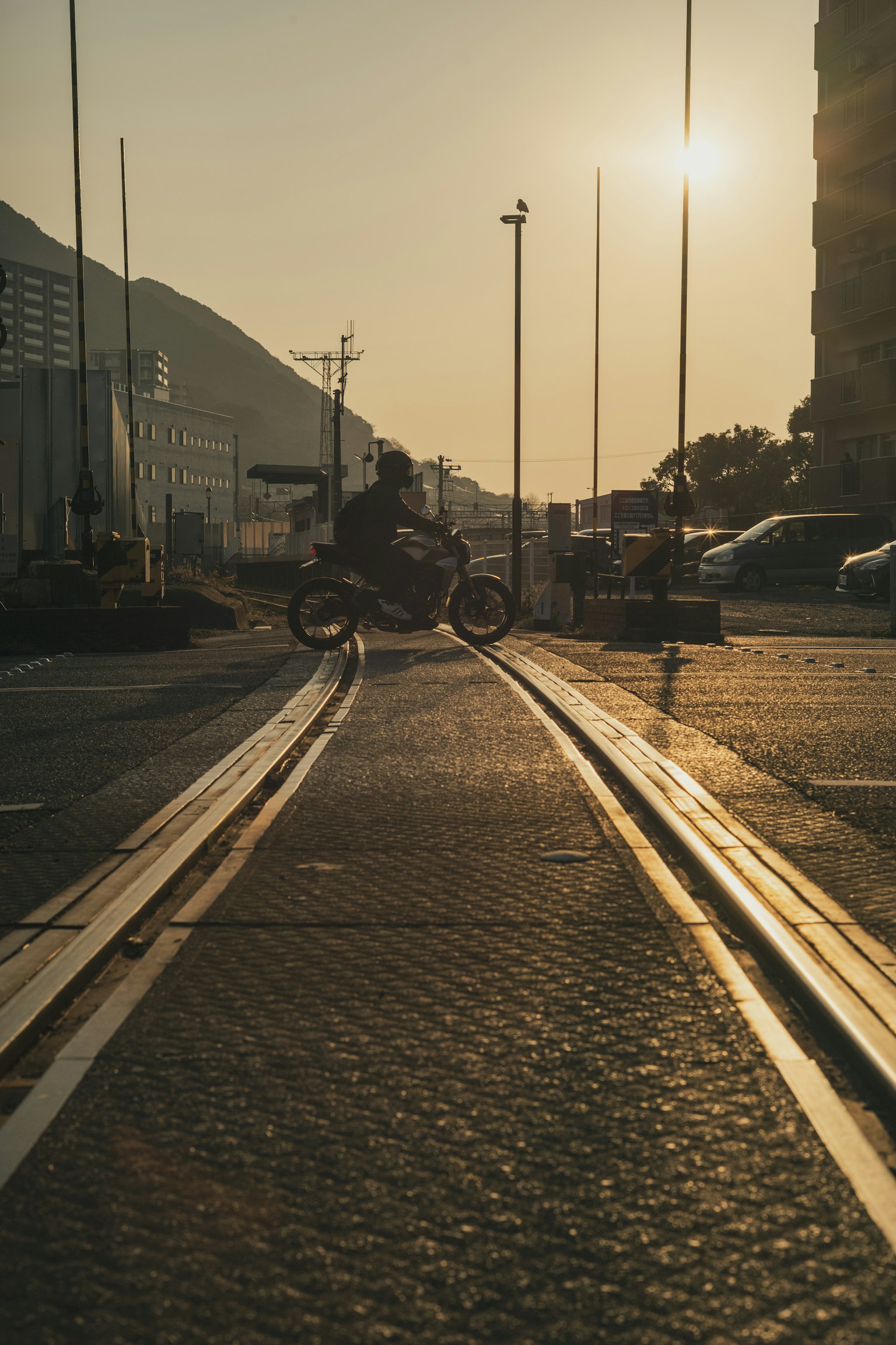 Rails de tramway avec une moto silhouettée contre le coucher de soleil