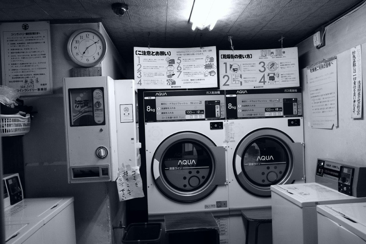 Interior de una lavandería con máquinas de lavar y secar en blanco y negro