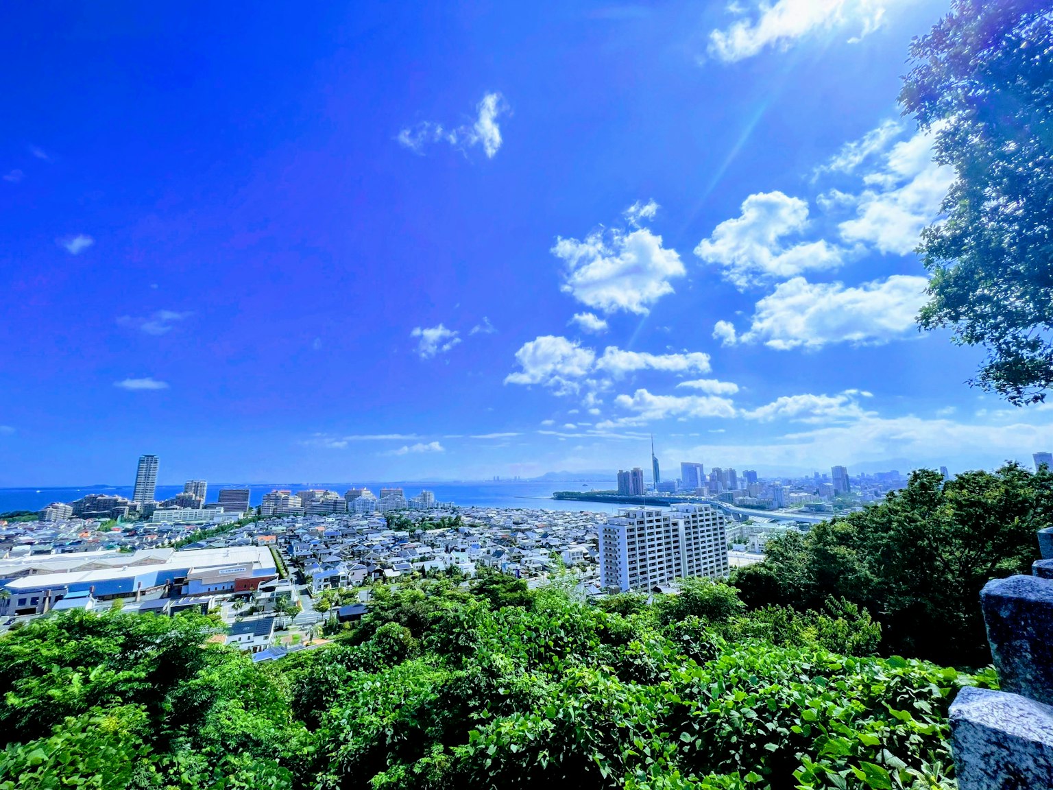 ทิวทัศน์เมืองที่สวยงามท้องฟ้าสีฟ้าและเมฆต้นไม้สีเขียวและทะเลที่มองเห็นได้