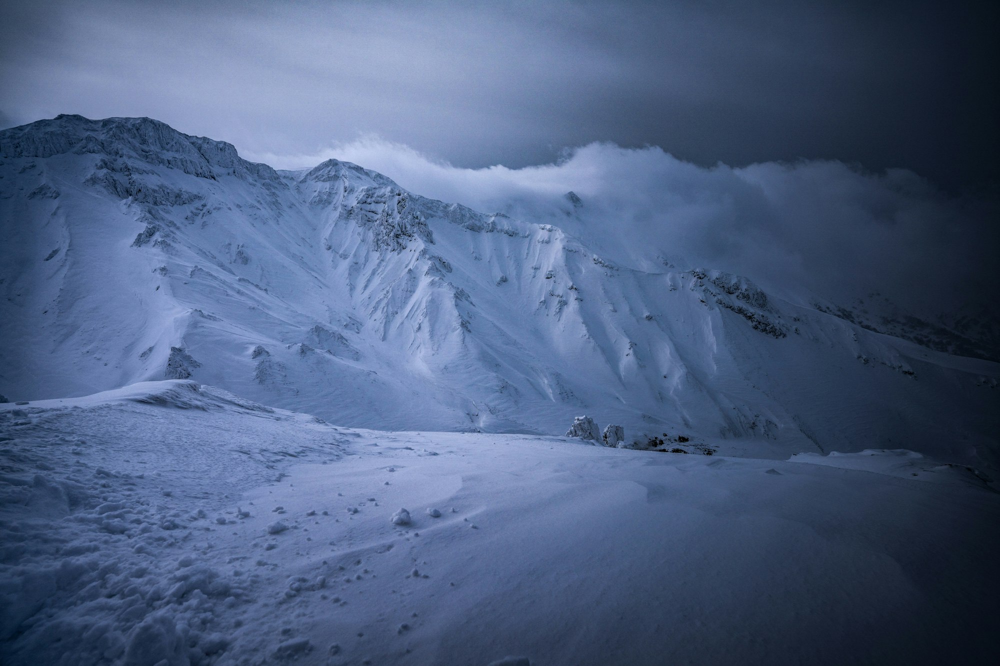 雪原と山稜が広がる夜明け前の山岳風景