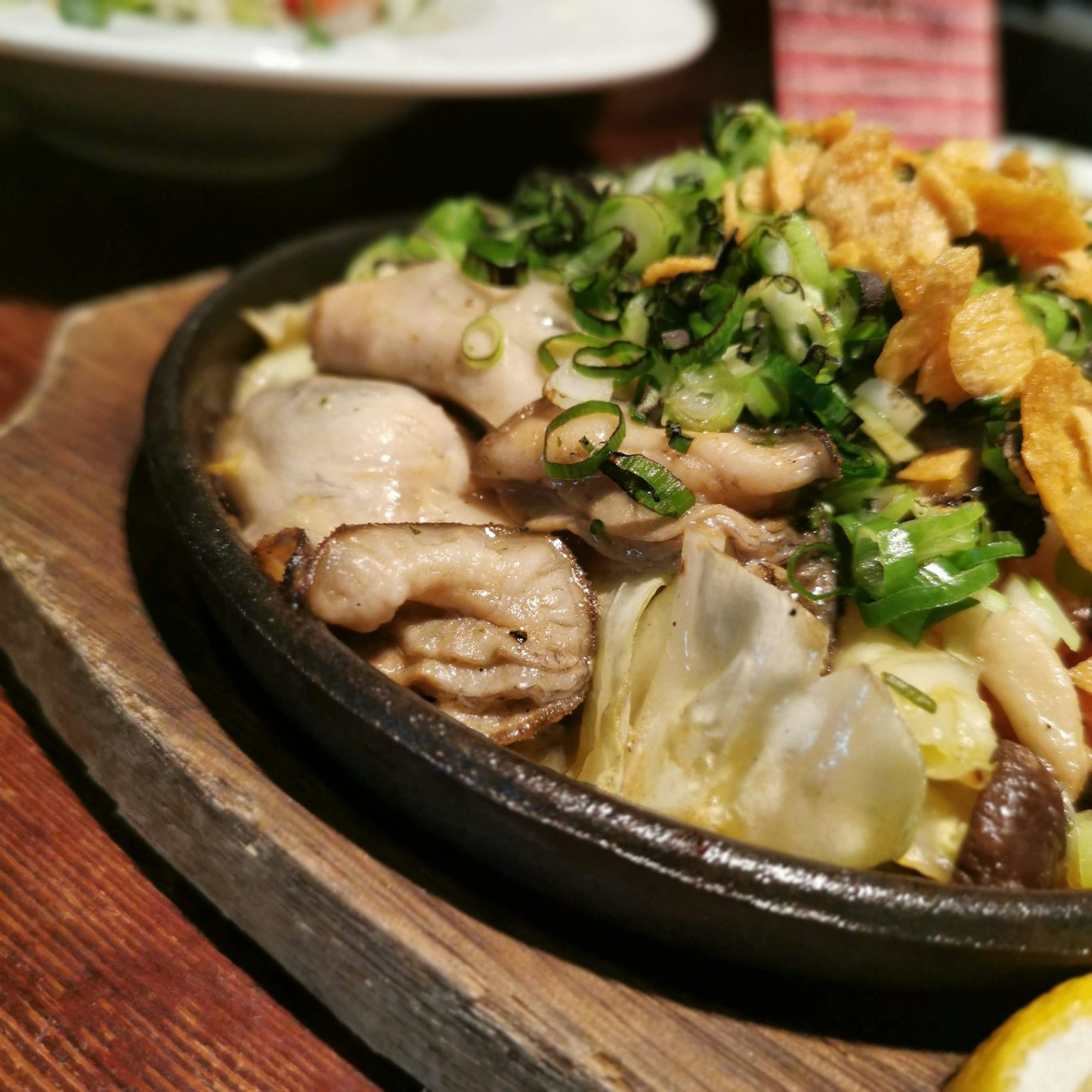 Piatto sfrigolante di pollo e verdure su una piastra calda, colori vivaci e guarnizioni aromatiche