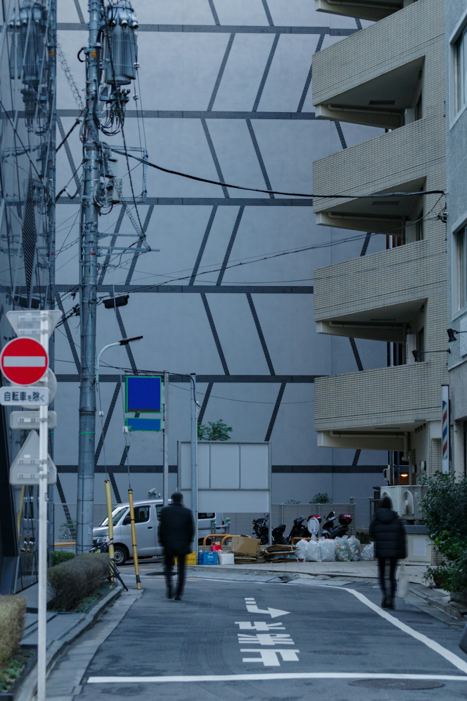 Strada urbana moderna con persone che camminano e un muro a motivi geometrici