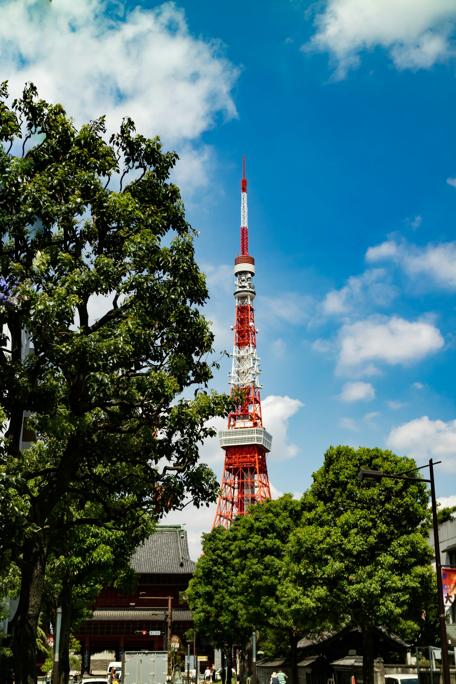 Tour de Tokyo s'élevant parmi des arbres verts sous un ciel bleu vif