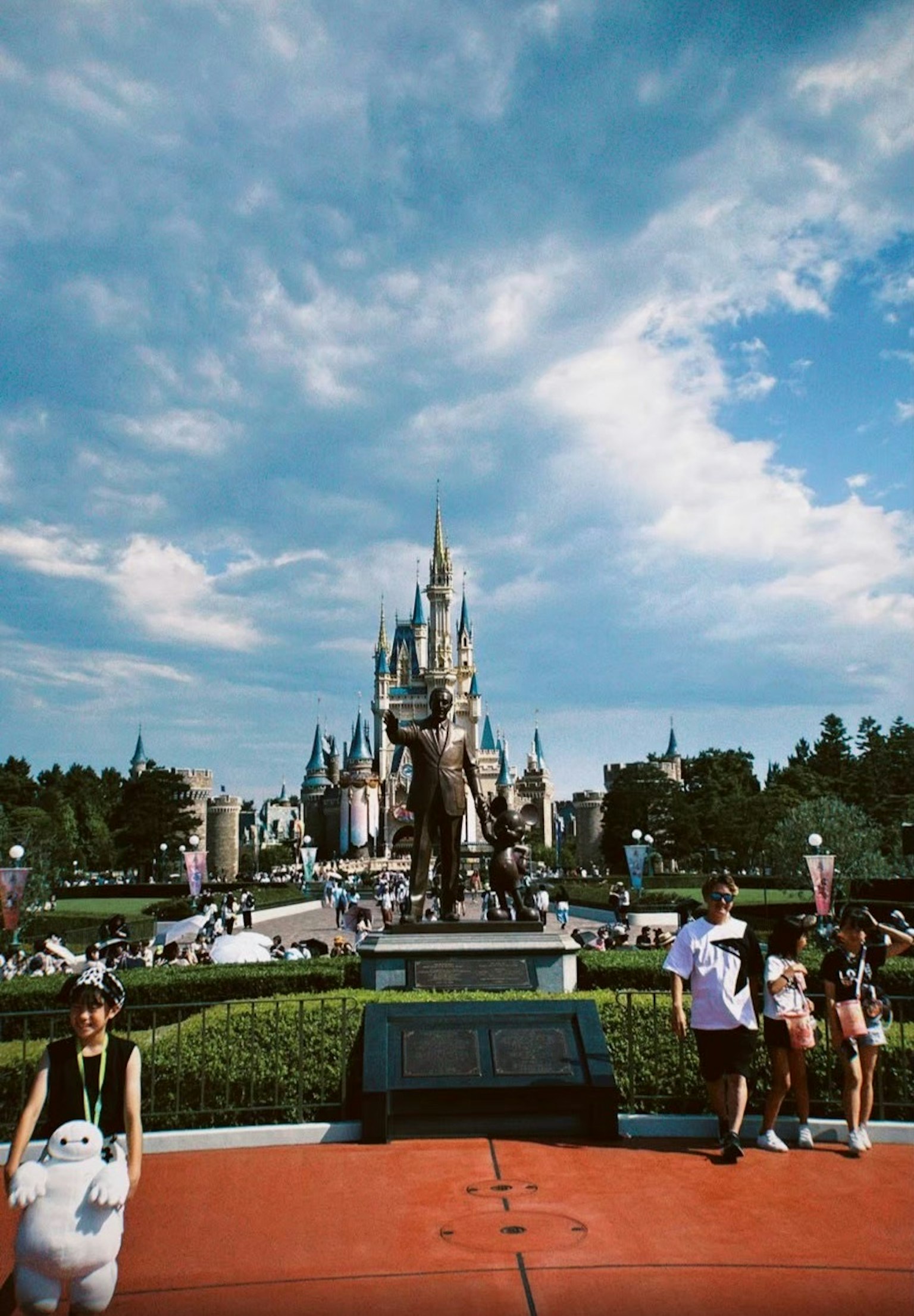 Château de Cendrillon dans un parc Disney avec des visiteurs et un ciel bleu