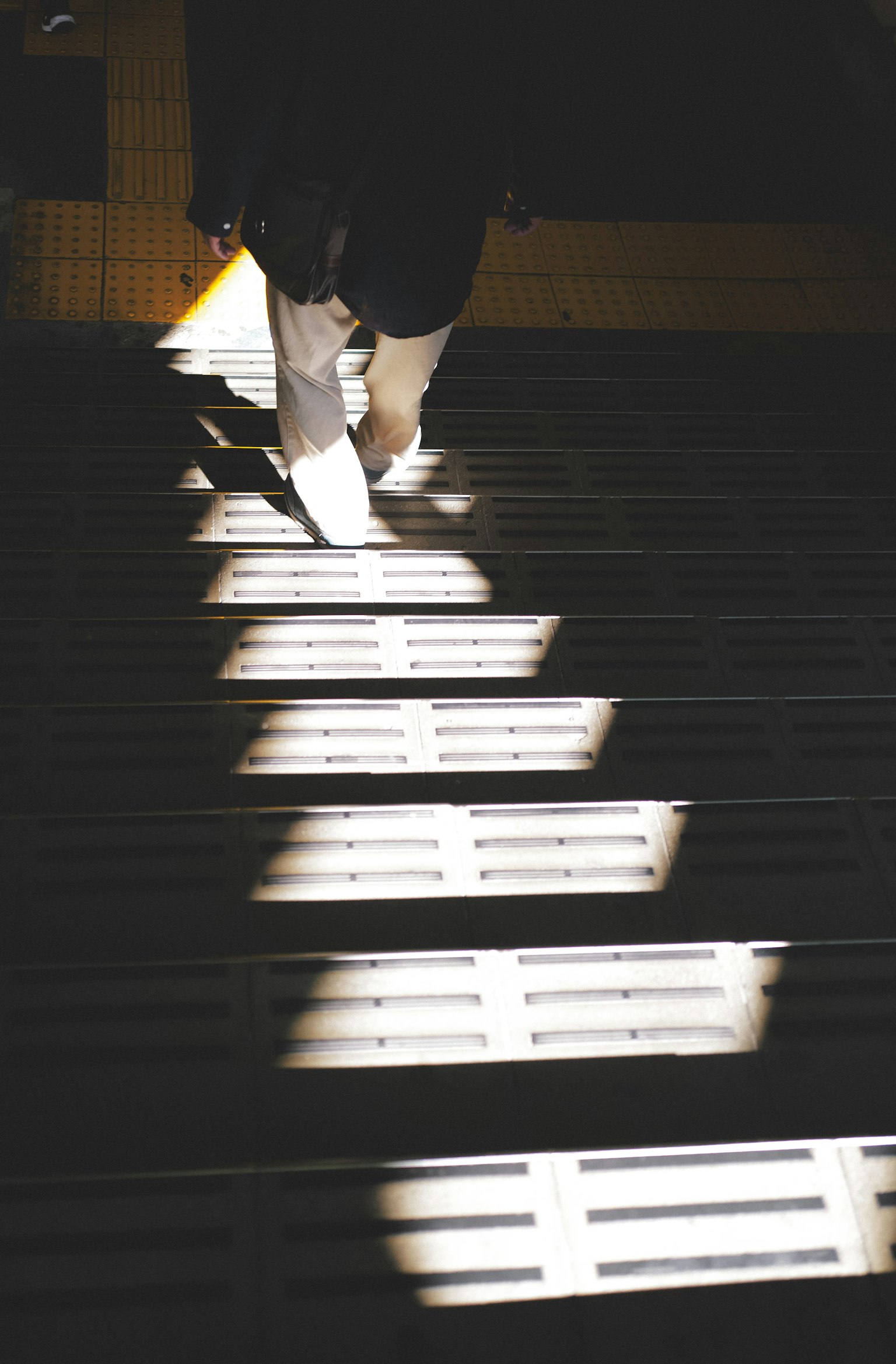 Person walking up stairs illuminated by light