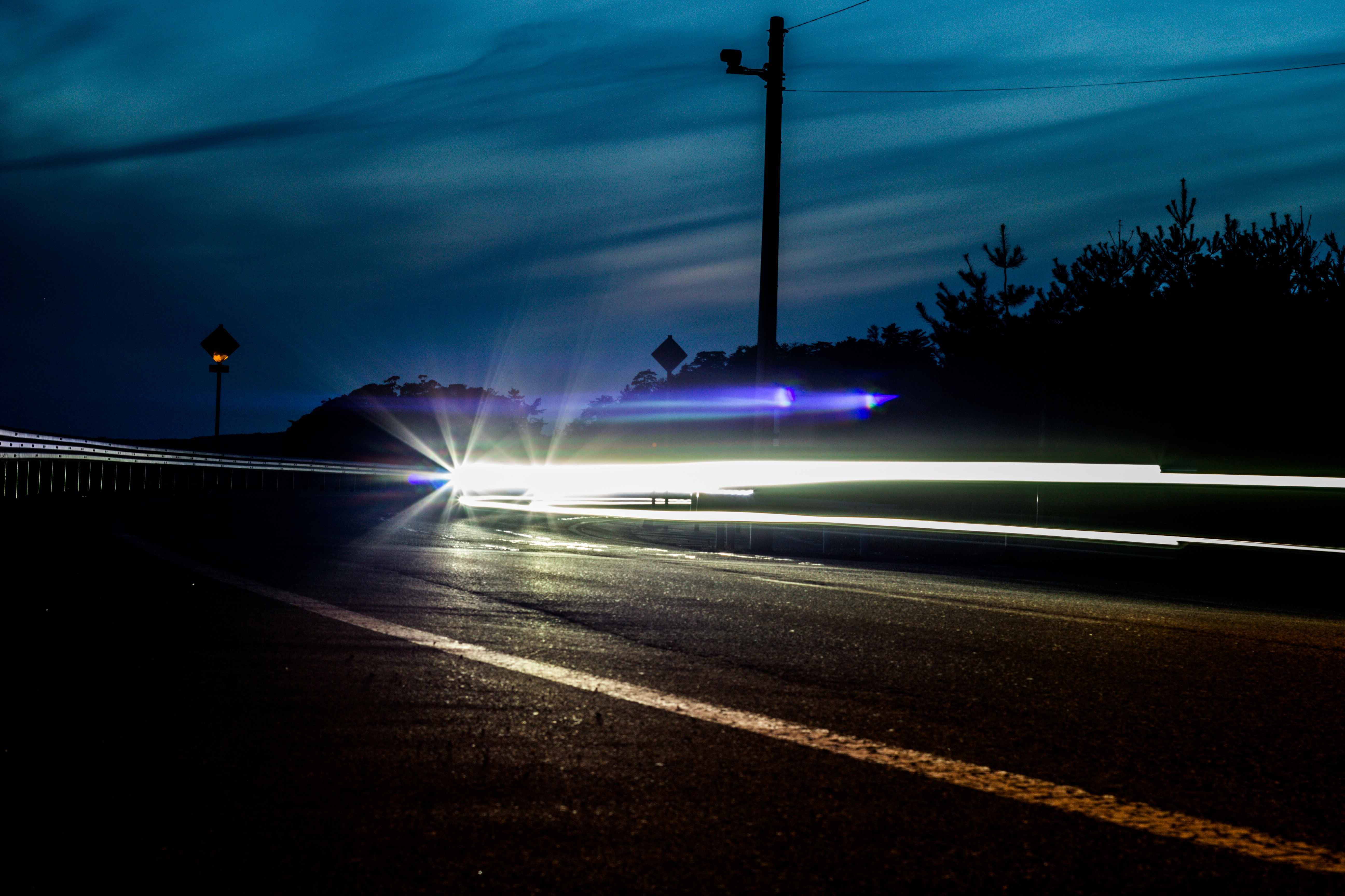 車のヘッドライトが伸びる夜の道路でレーザービームのような光