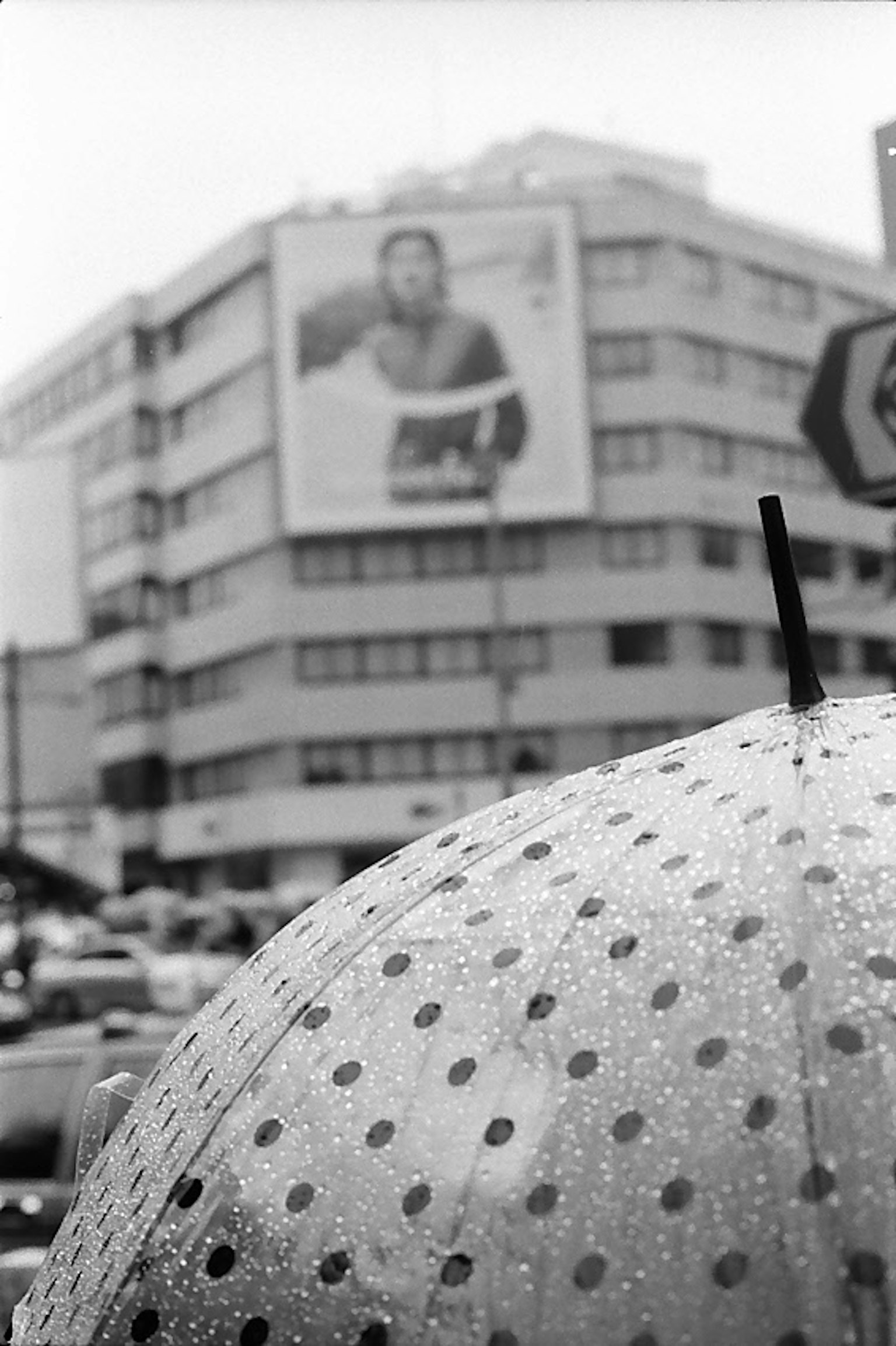 A street scene with a polka dot umbrella in the foreground and a large advertisement on a building