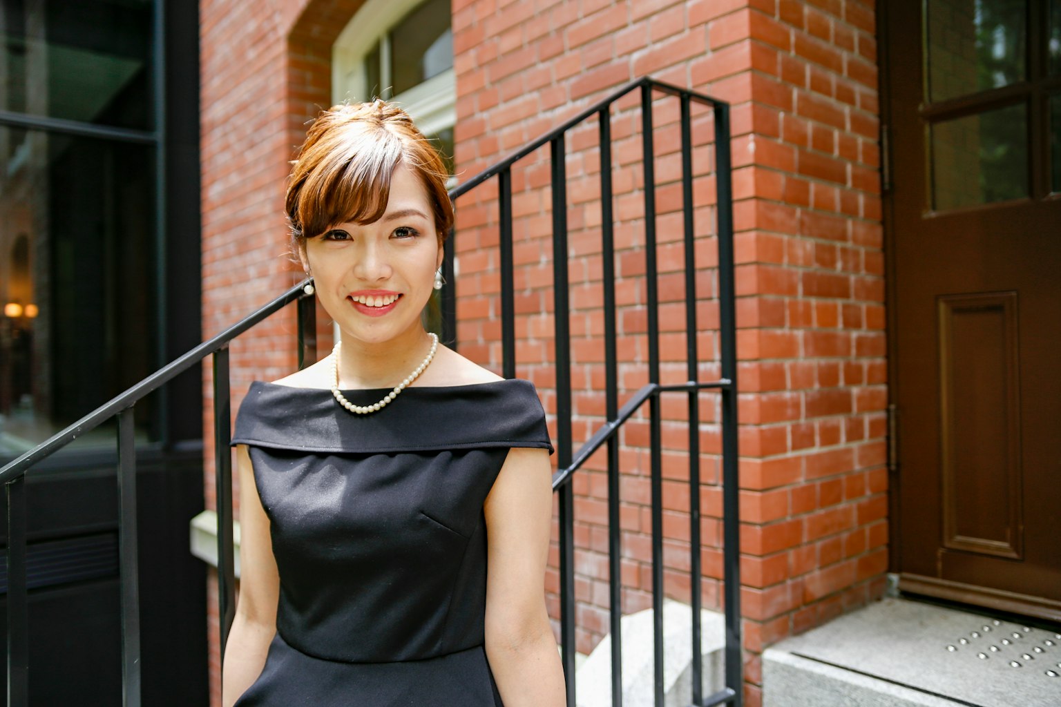 一位穿著漂亮黑色裙子的女性站在磚砌建築前