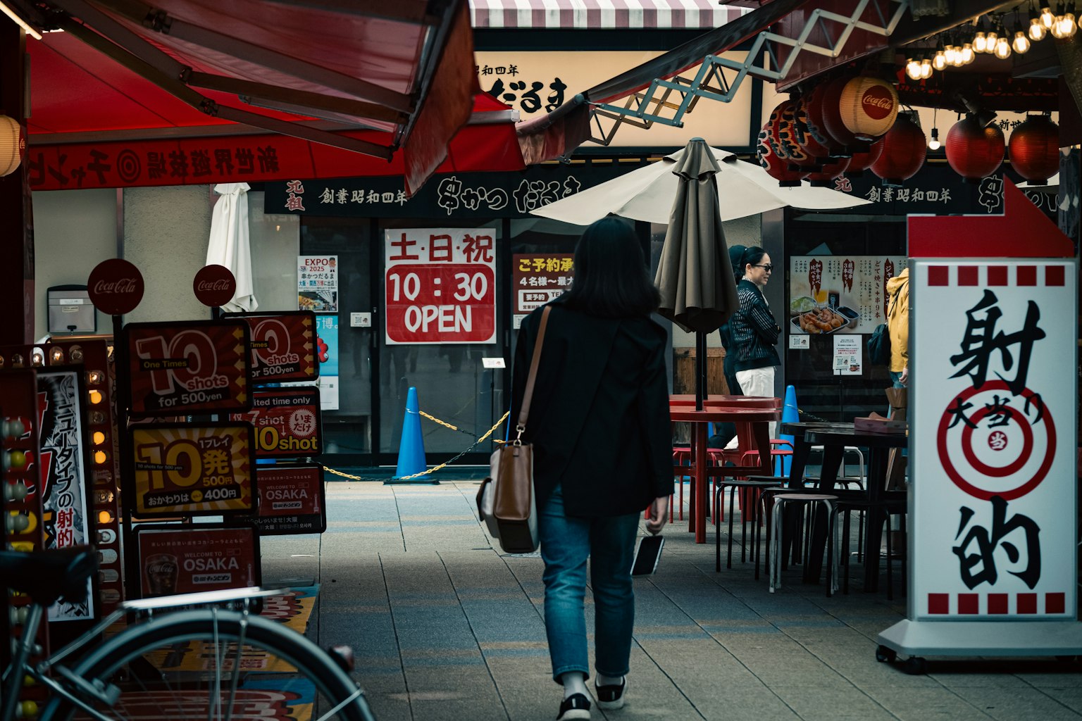 人が通りを歩いている商店街の風景 赤いテントと看板が並ぶ