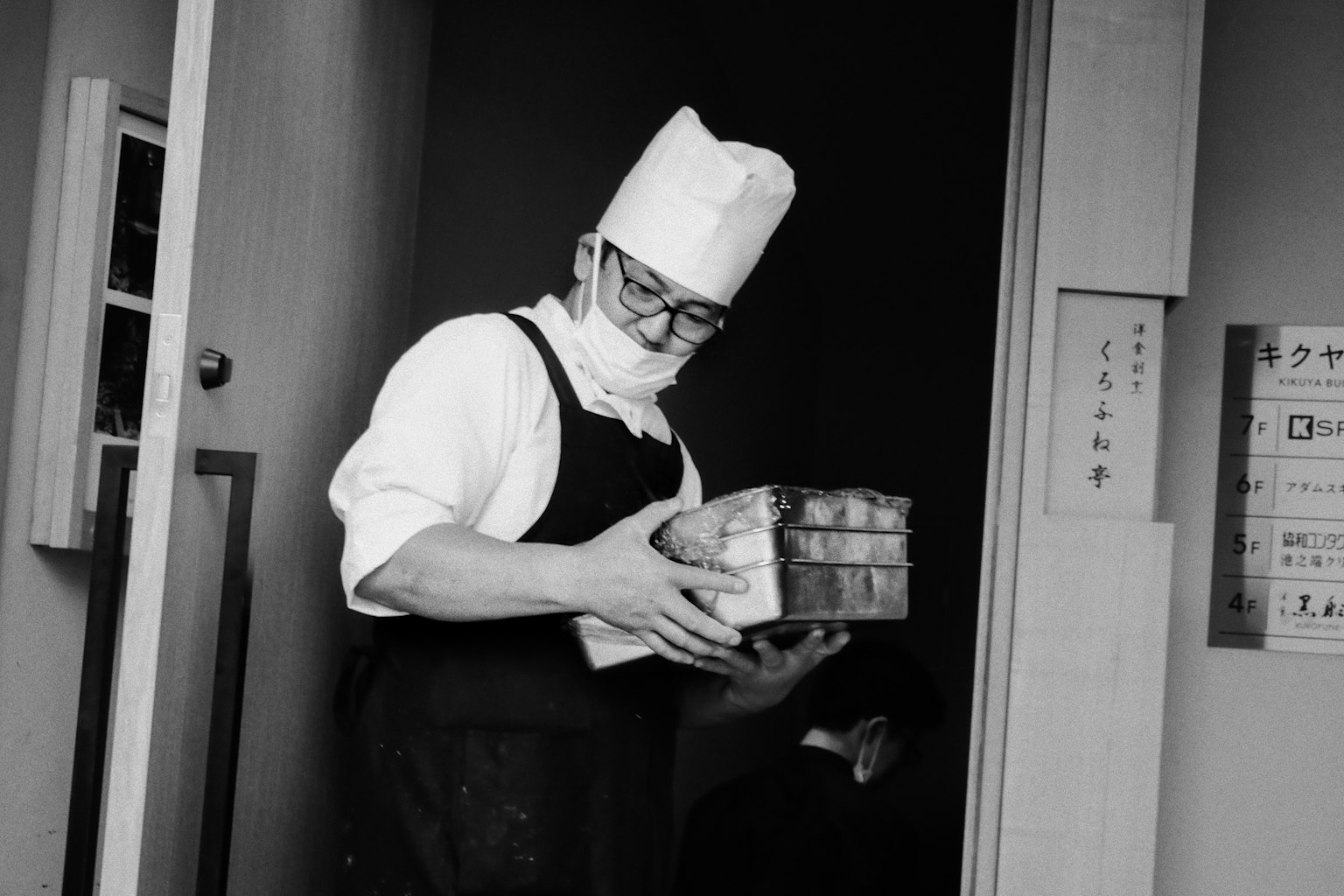 シェフが箱を持って出てくるモノクロの画像