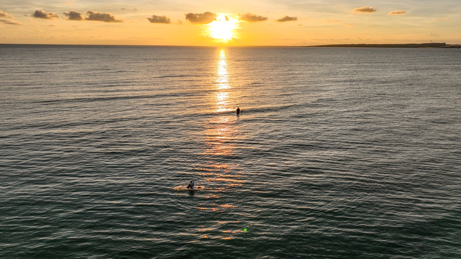 Menschen surfen im Ozean bei Sonnenuntergang